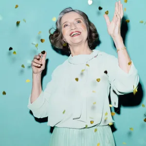 Eine Frau steht unter einem goldenen Konfetti-Regen.