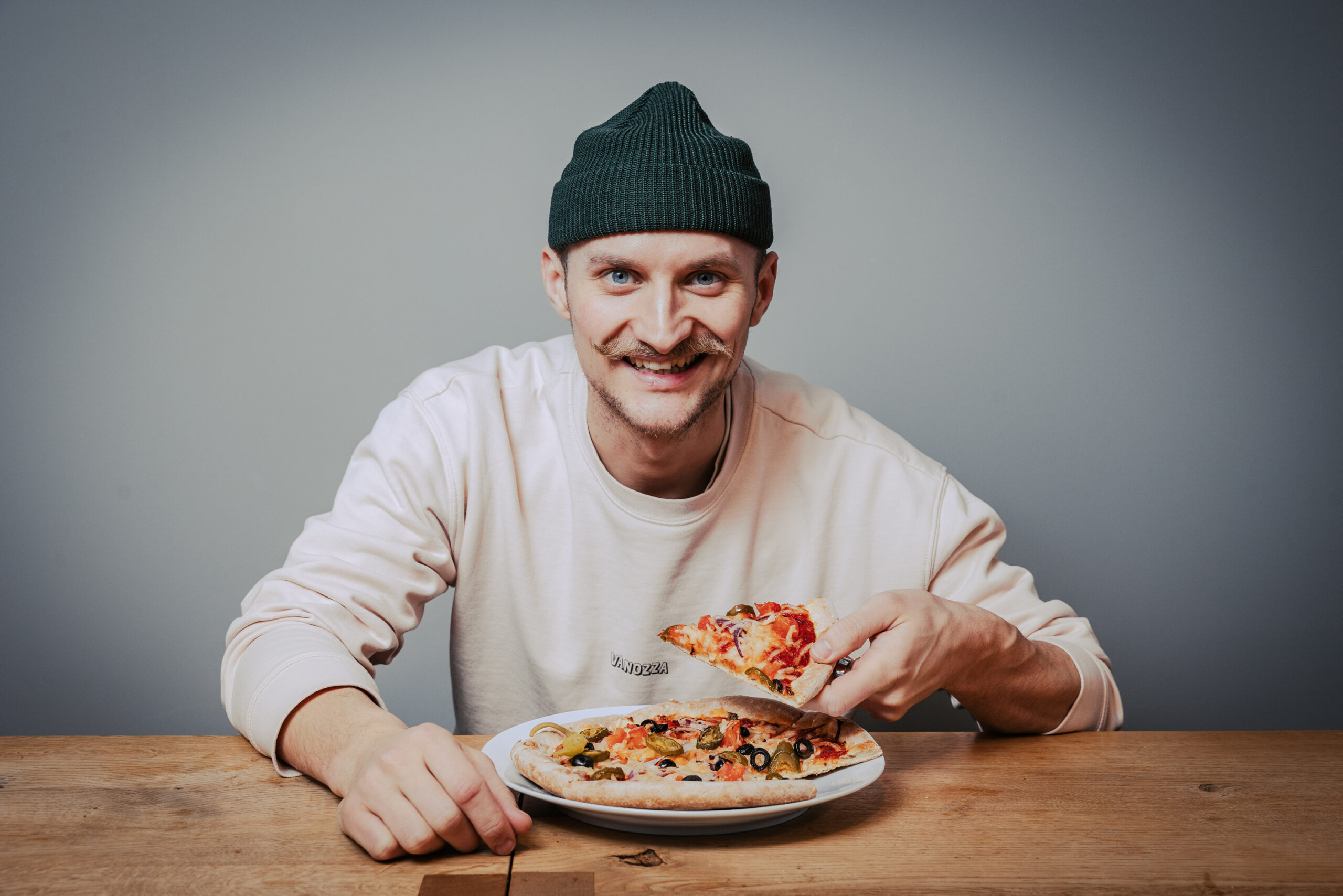 Nico Hansen mit einem Stück Pizza in der Hand.