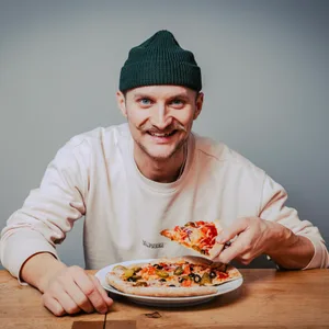Nico Hansen mit einem Stück Pizza in der Hand.