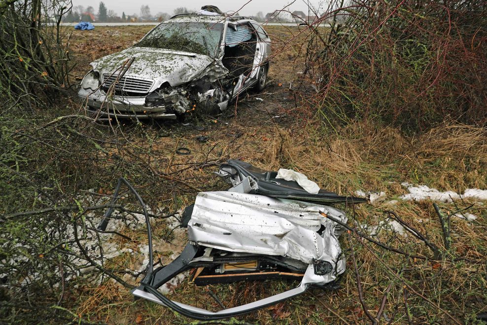 Ein silbernes Auto steht stark demoliert im Graben.
