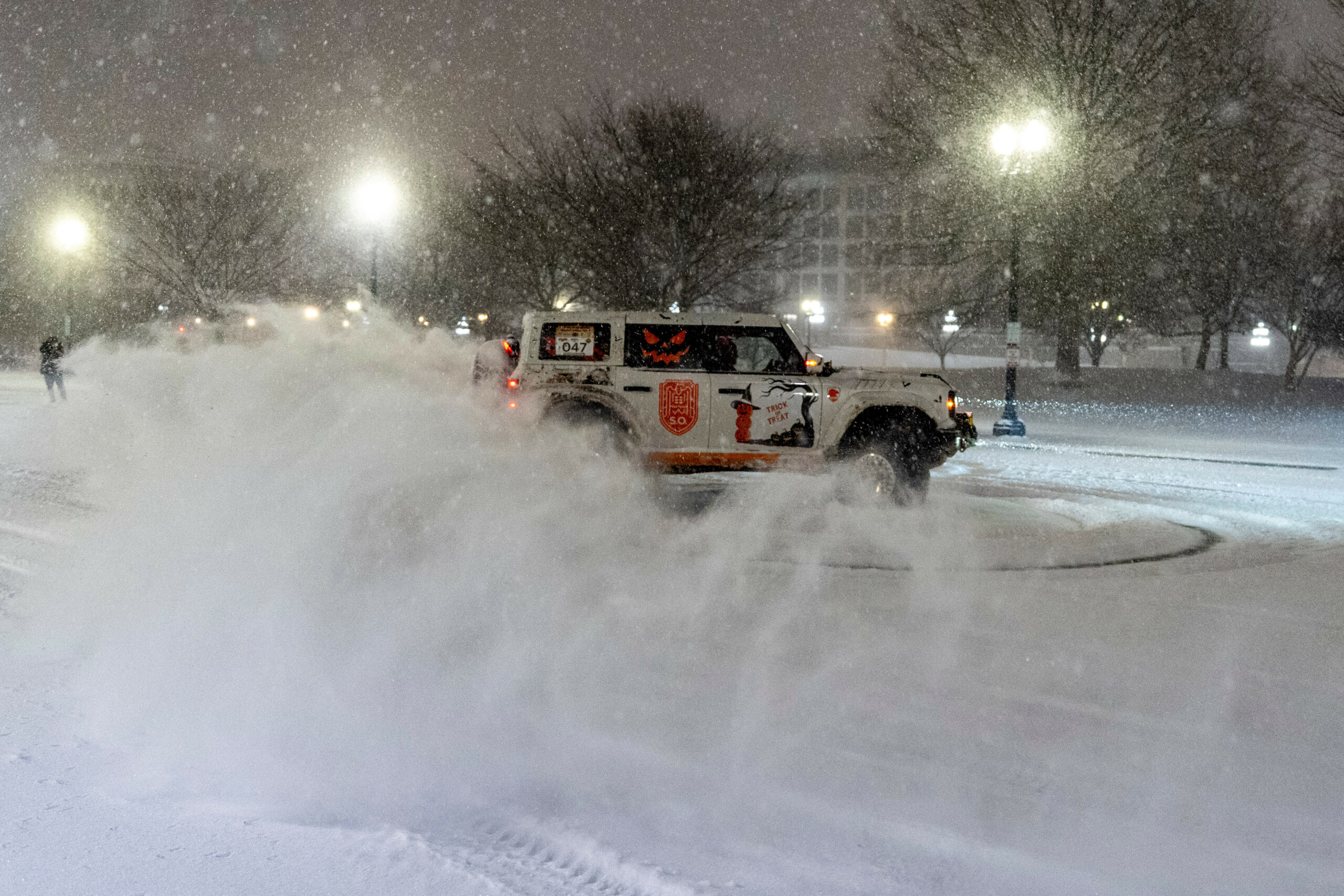 Ein Fahrzeug dreht Kreise auf einem verschneiten Parkplatz, während der Schnee fällt.