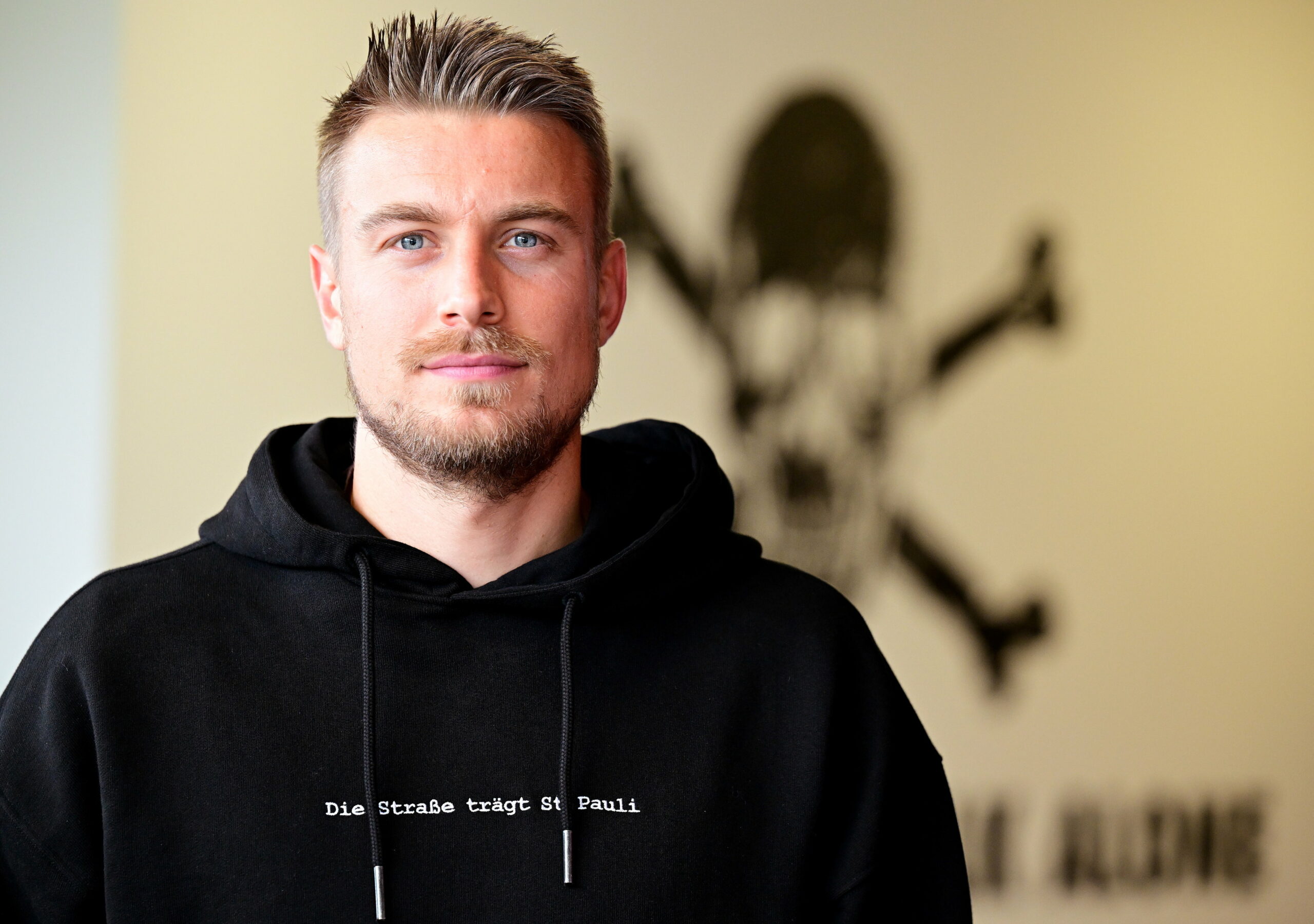 Hauke Wahl vor einem Totenkopflogo an der Kollaustraße