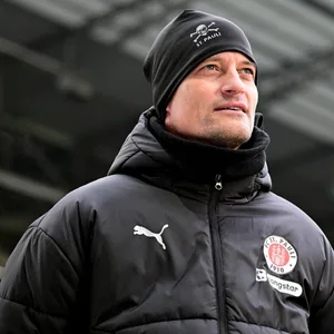 St. Pauli-Trainer Alexander Blessin mit Mütze und Blick in die Weite beim Testspiel gegen Bremen.