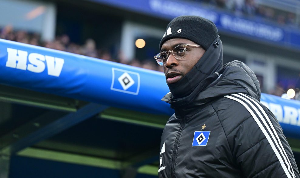 Albert Sambi Lokonga mit Mütze und Winterjacke vor der Auswechselbank