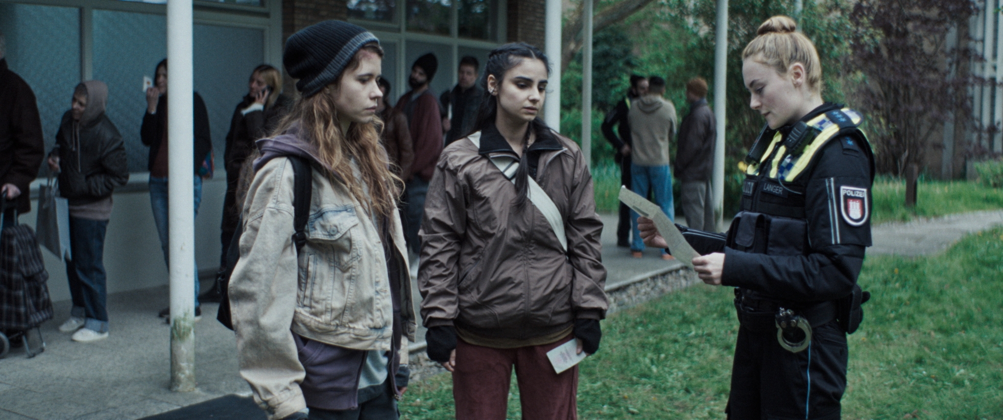 Die Charaktere Laura, und Julia treffen zum ersten Mal vor einer Lebensmittelausgabe aufeinander.