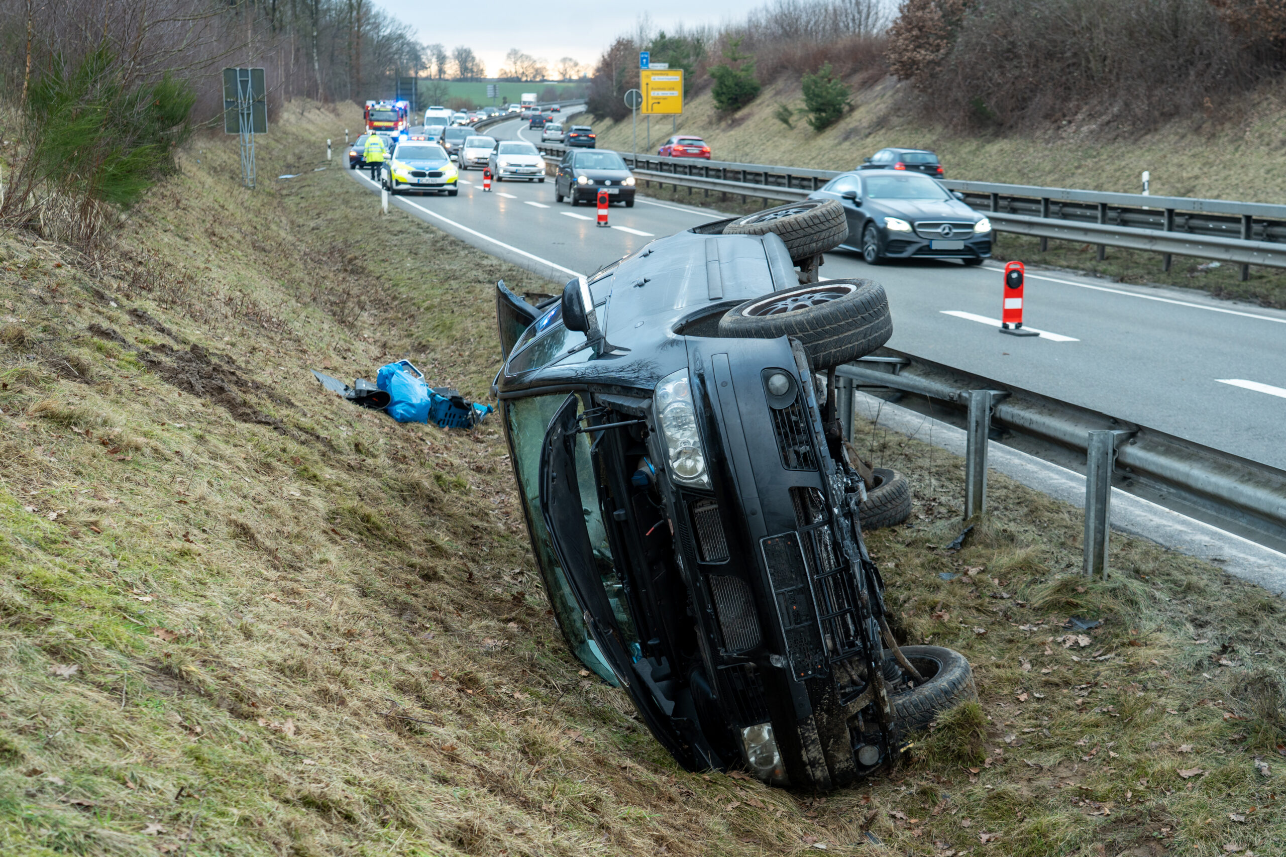 Ein verunfalltes Auto liegt neben der Leitplanke auf der Seite.