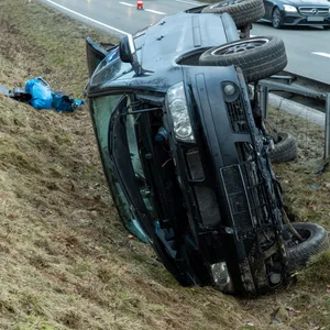 Ein verunfalltes Auto liegt neben der Leitplanke auf der Seite.