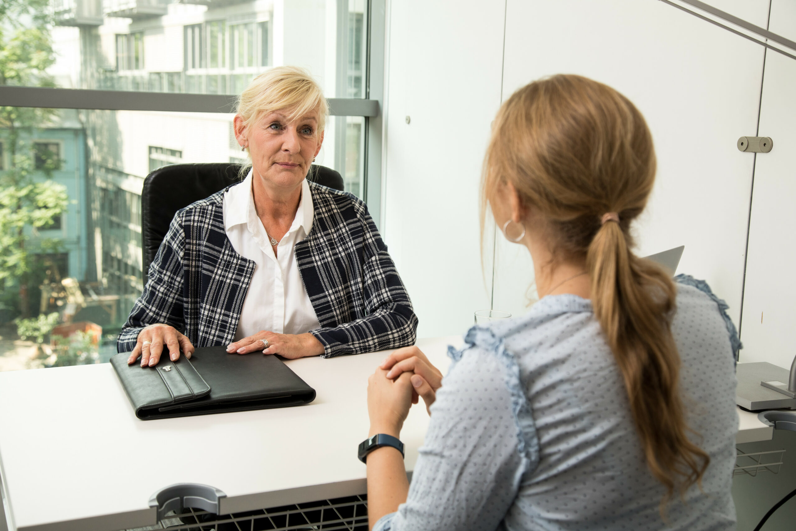 Zwei Frauen sitzen sich an einem Arbeitstisch gegenüber.