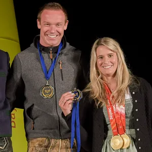 Felix Loch und Natalie Geisenberger posieren mit Medaillen auf einem Podium