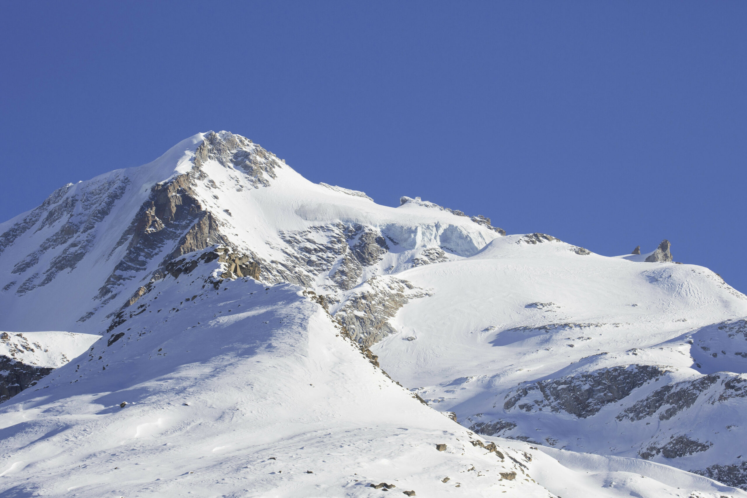 Ein verschneiter Berg vor blauem Himmel.