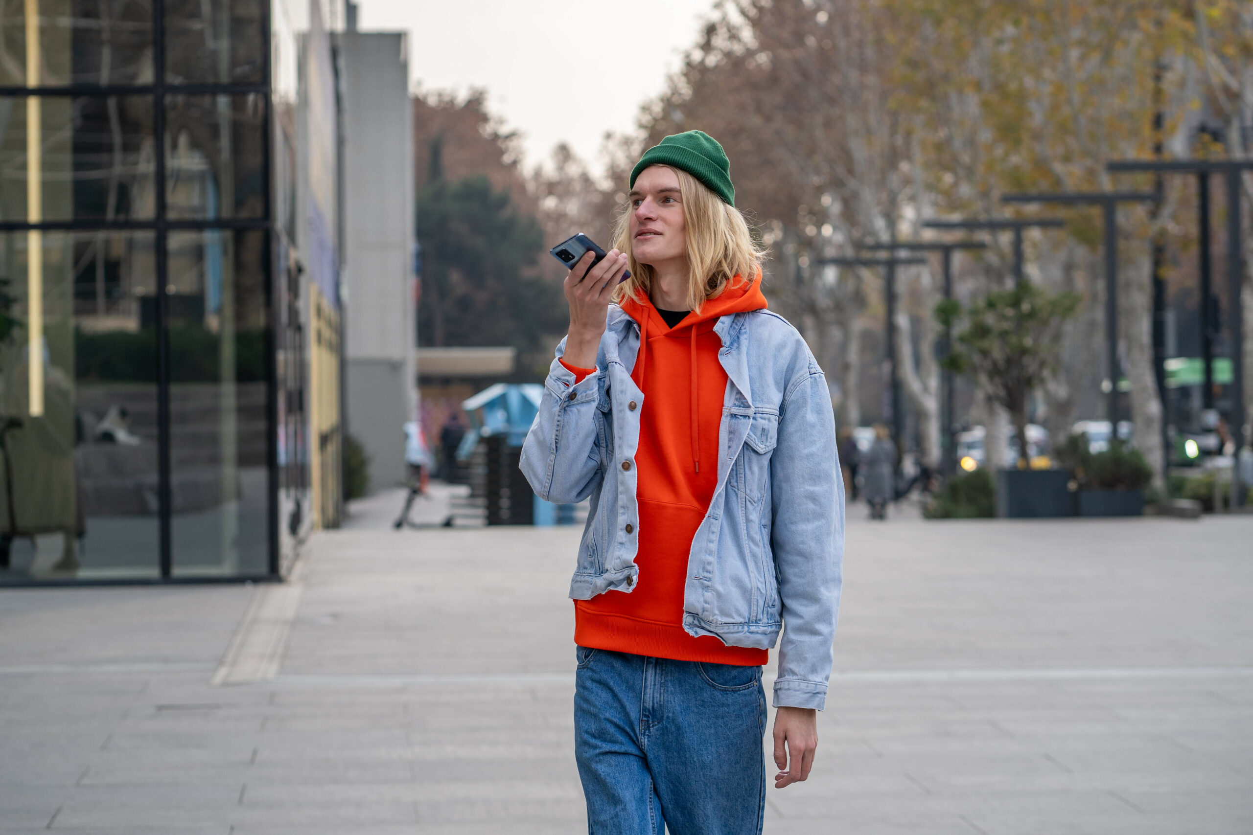 Junger Mann mit Mütze hält sich Handy vor den Mund