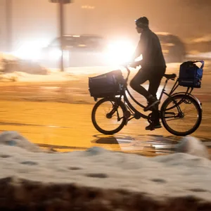 Ein Mann fährt am Morgen im Nebel und bei Tauwetter über eine Straße.