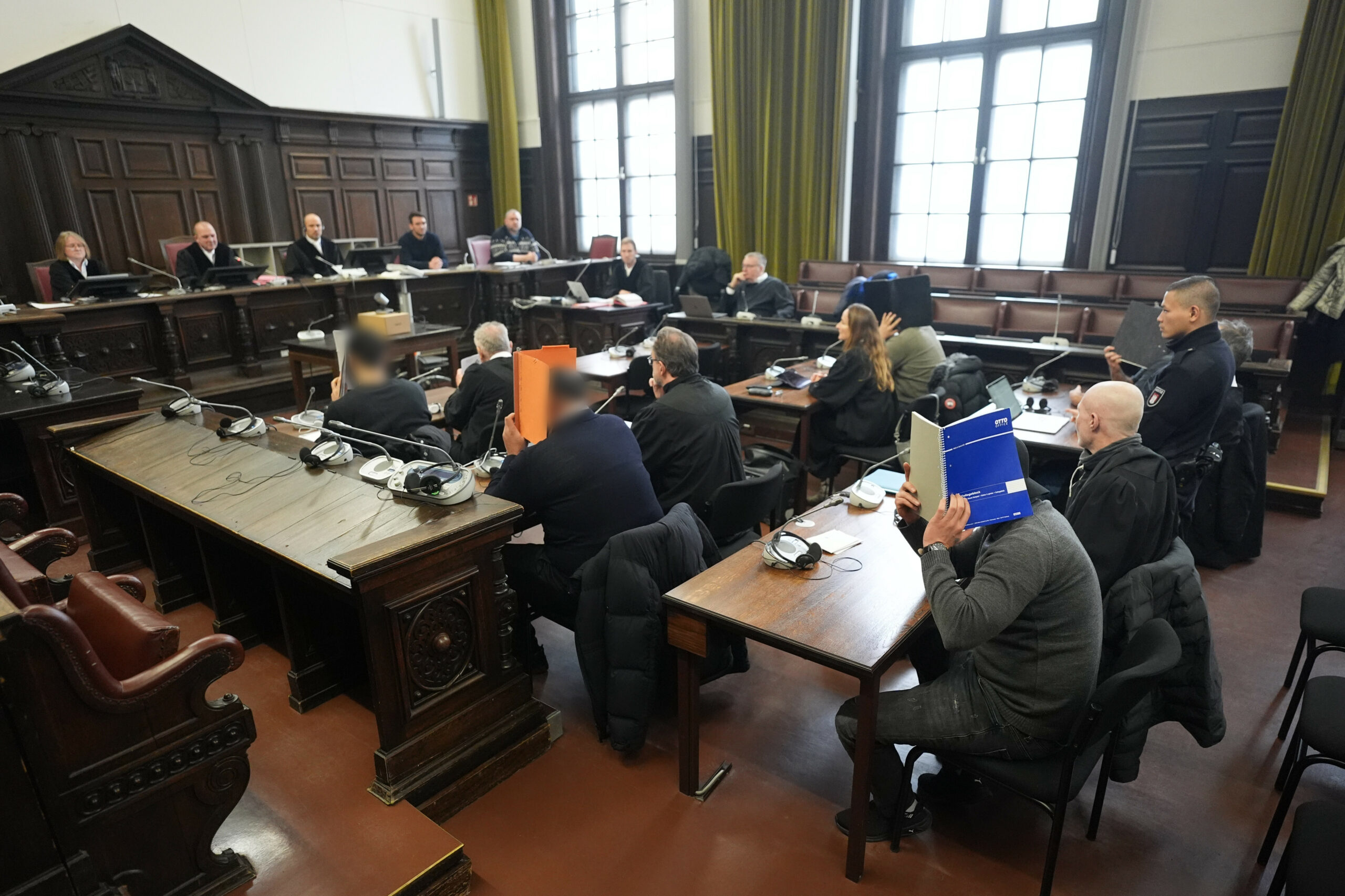 Die Angeklagten sitzen zu Beginn im Prozess wegen versuchten Totschlags und gefährlicher Körperverletzung neben ihren Anwälten im Sitzungssaal im Strafjustizgebäude.