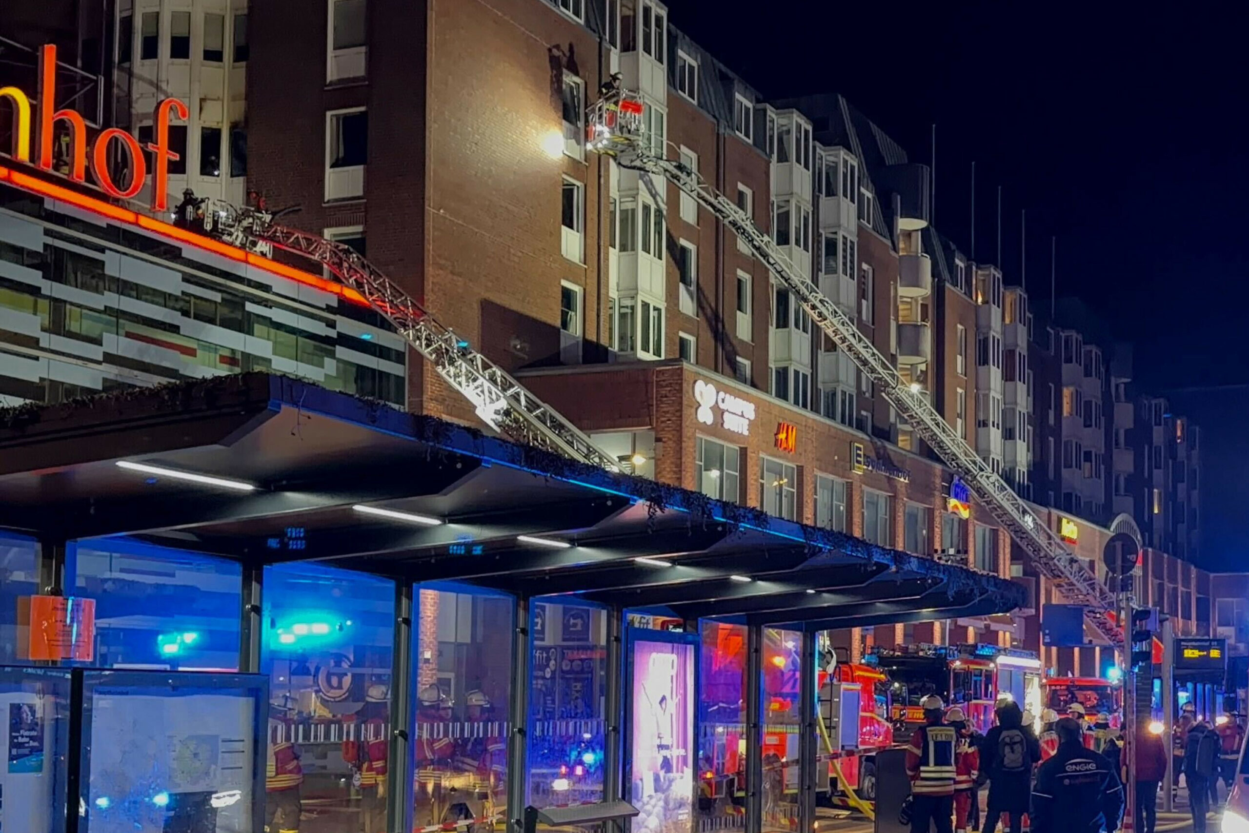 Einsatzkräfte der Feuerwehr sind auf Drehleitern an einem Wohnhaus neben dem Einkaufszentrum Sophienhof im Einsatz.