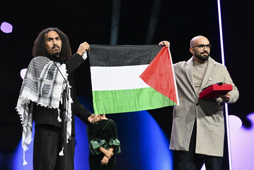 Der Regisseur Abdallah Alkhatib hält eine palästinensische Flagge in die Höhe.