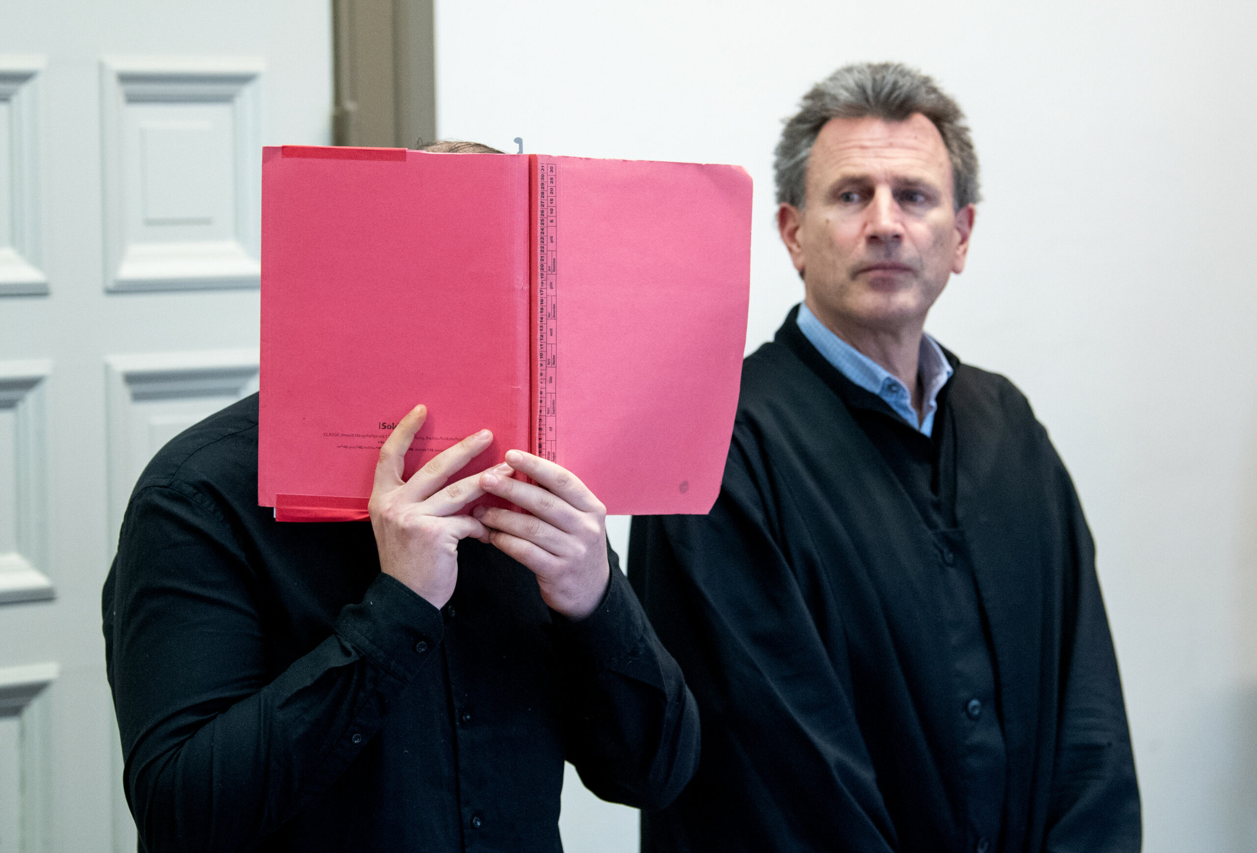 Der 25-jährige Angeklagte (l.) steht im Landgericht im Sitzungssaal neben seinem Verteidiger.