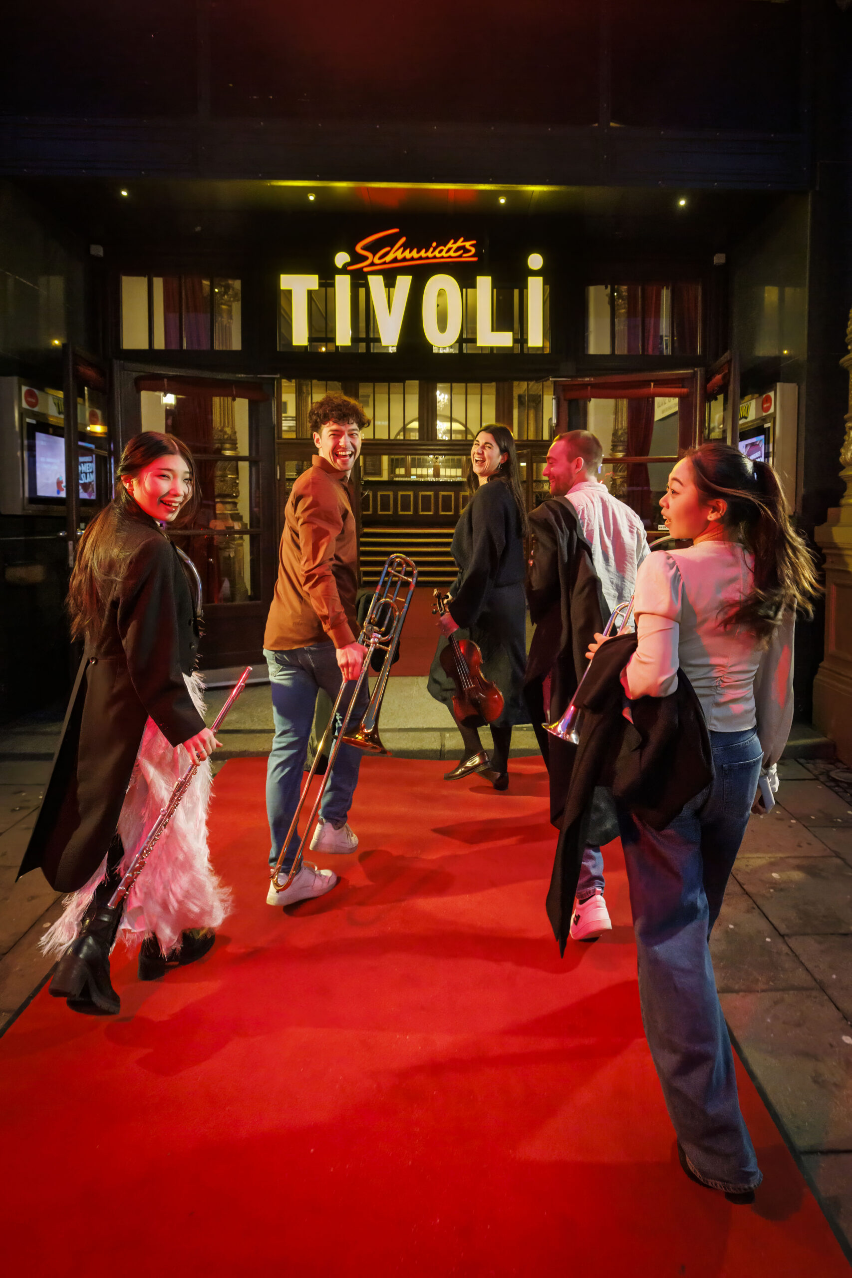 Musikerinnen und Musiker des Philharmonischen Staatsorchesters laufen auf den Eingang des „Schmidts Tivoli“ zu.