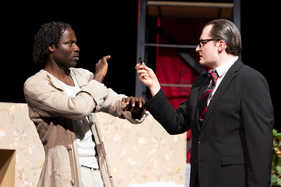 Ein Mann in Anzug steht einem anderen Mann gegenüber.