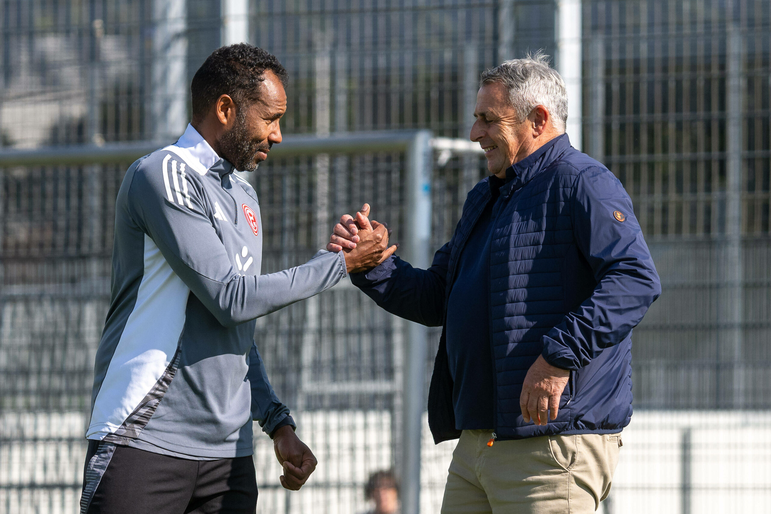 Daniel Thioune und Klaus Allofs klatschen sich beim Training ab