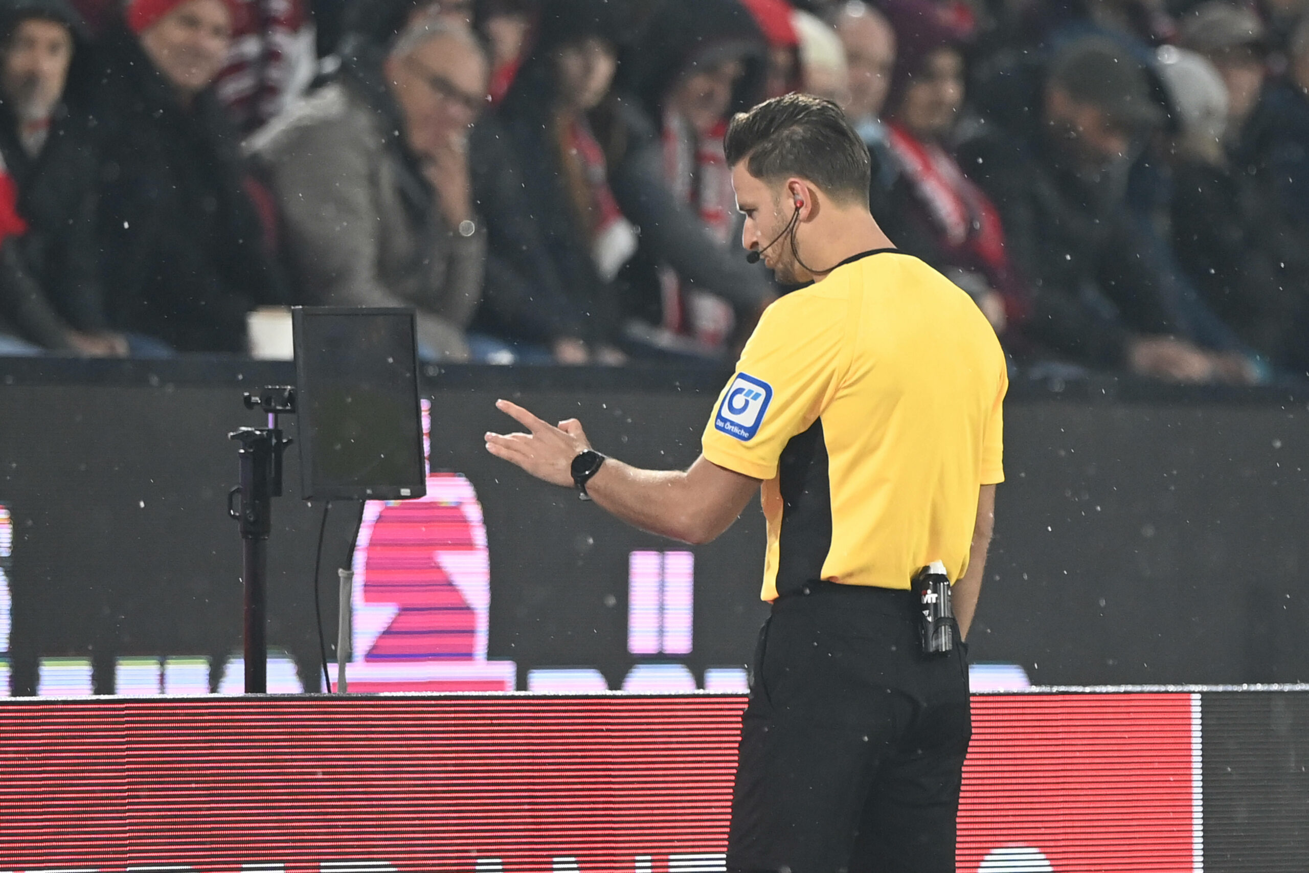 Schiedsrichter Daniel Schlager schaut sich eine Szene am Monitor an