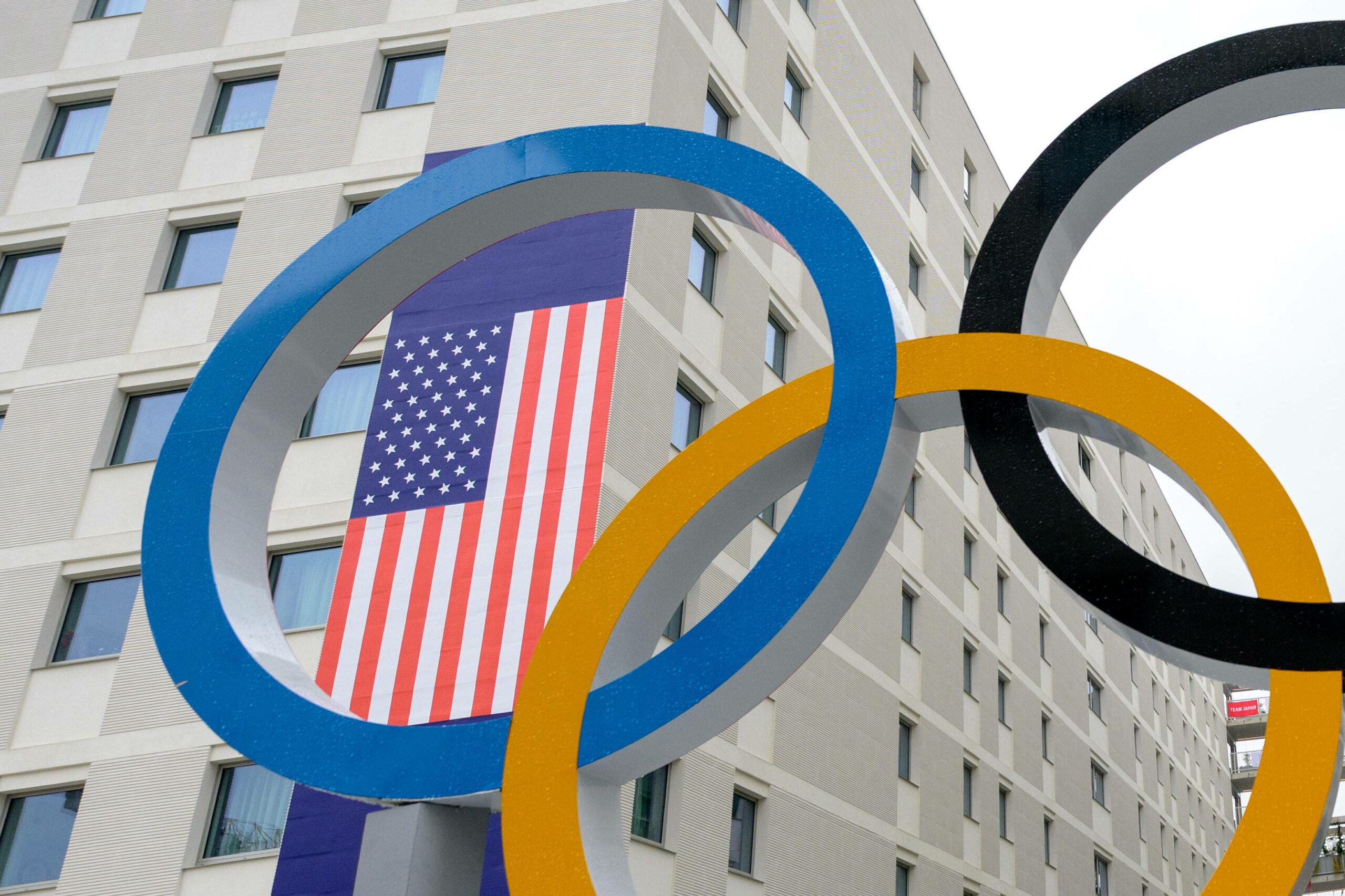 US-Flagge im Olympischen Dorf hinter Olympia-Ringen