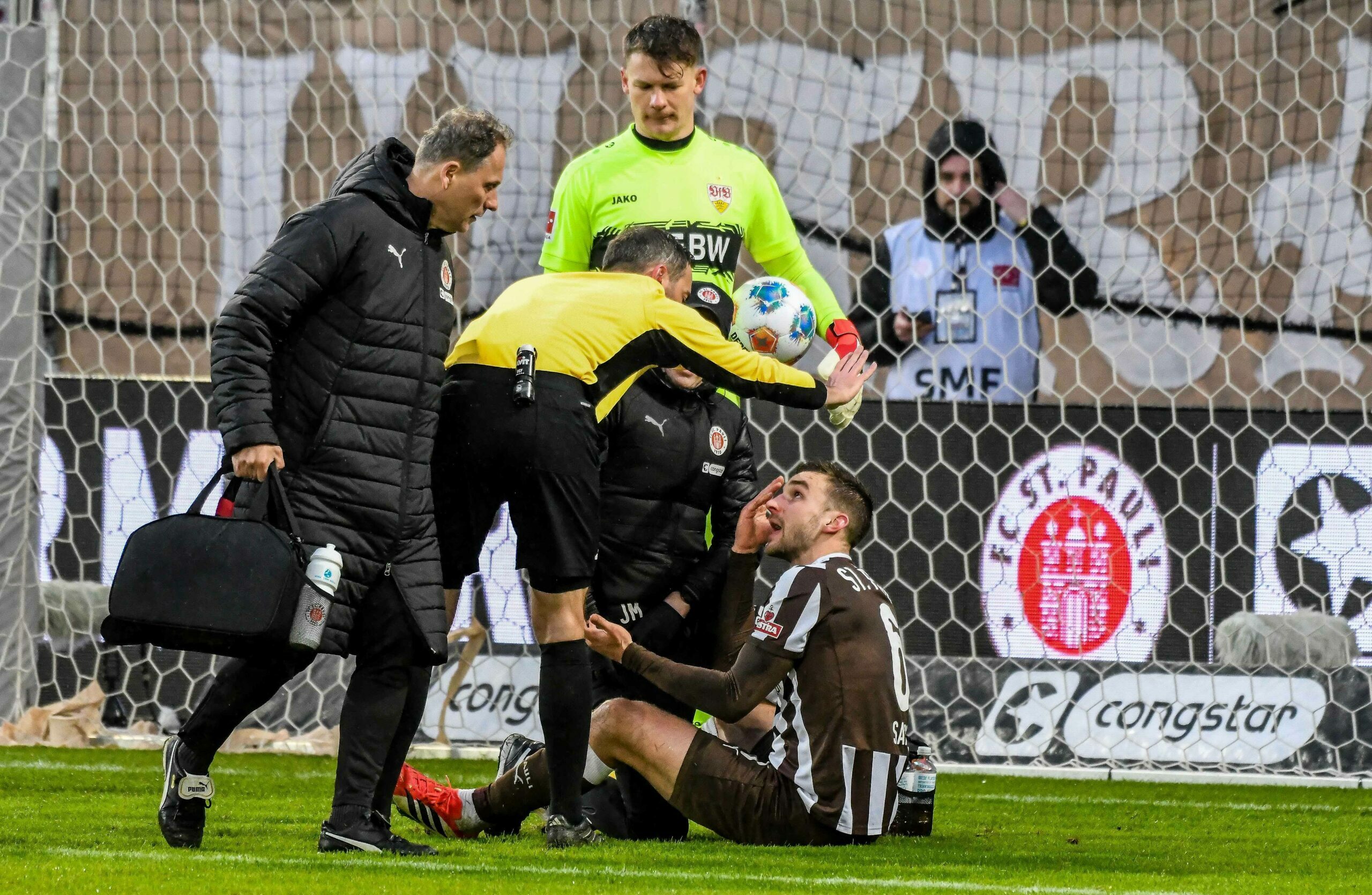 James Sands sitzt nach einem schmerzhaften Zusammenprall auf dem Boden und redet mit Schiedsrichter Benjamin Brand