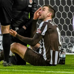 James Sands sitzt nach einem schmerzhaften Zusammenprall auf dem Boden und redet mit Schiedsrichter Benjamin Brand