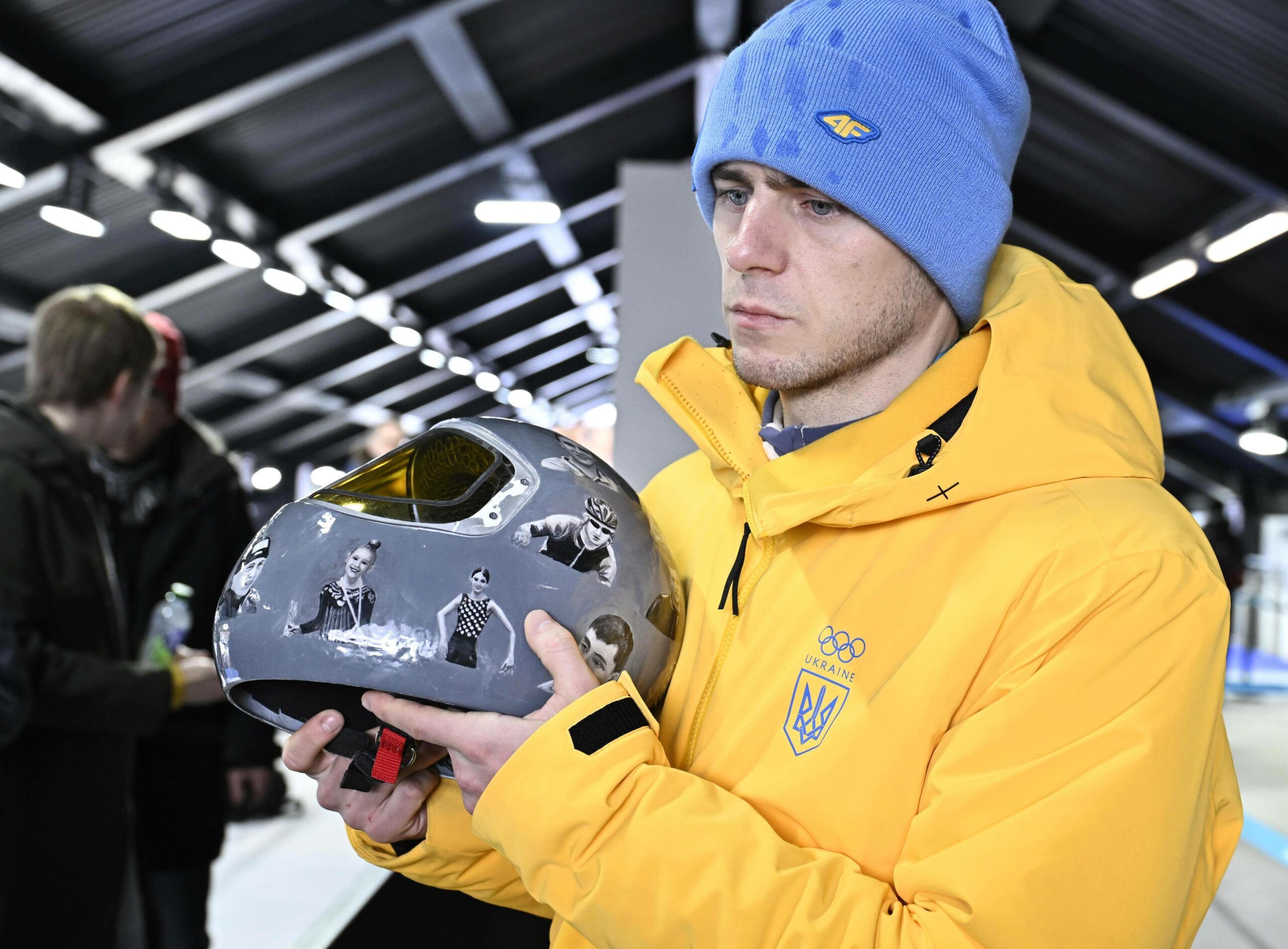 Vladyslav Heraskevych schaut enttäuscht mit seinem Helm in der Hand