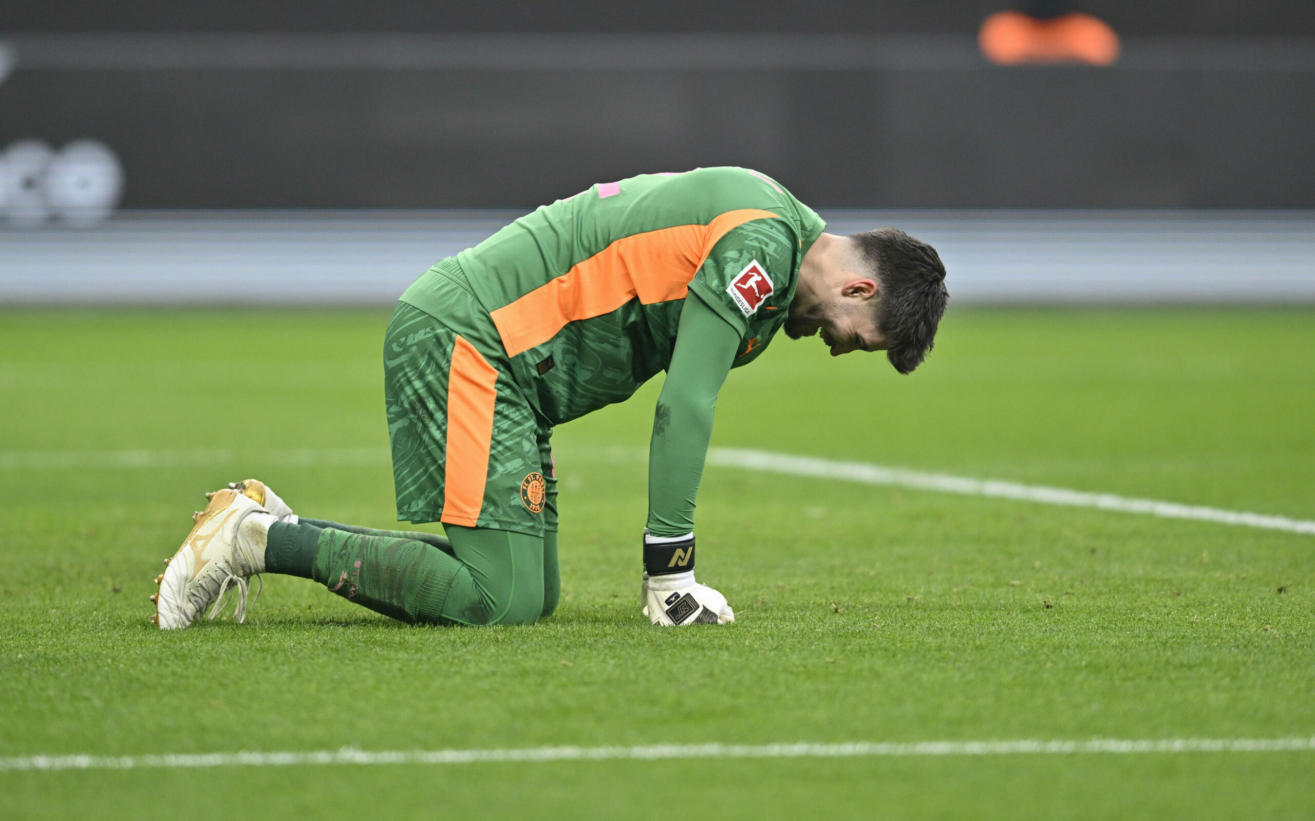 St. Pauli-Torwart Nikola Vasilj hockt frustriert auf allen Vieren auf dem Rasen