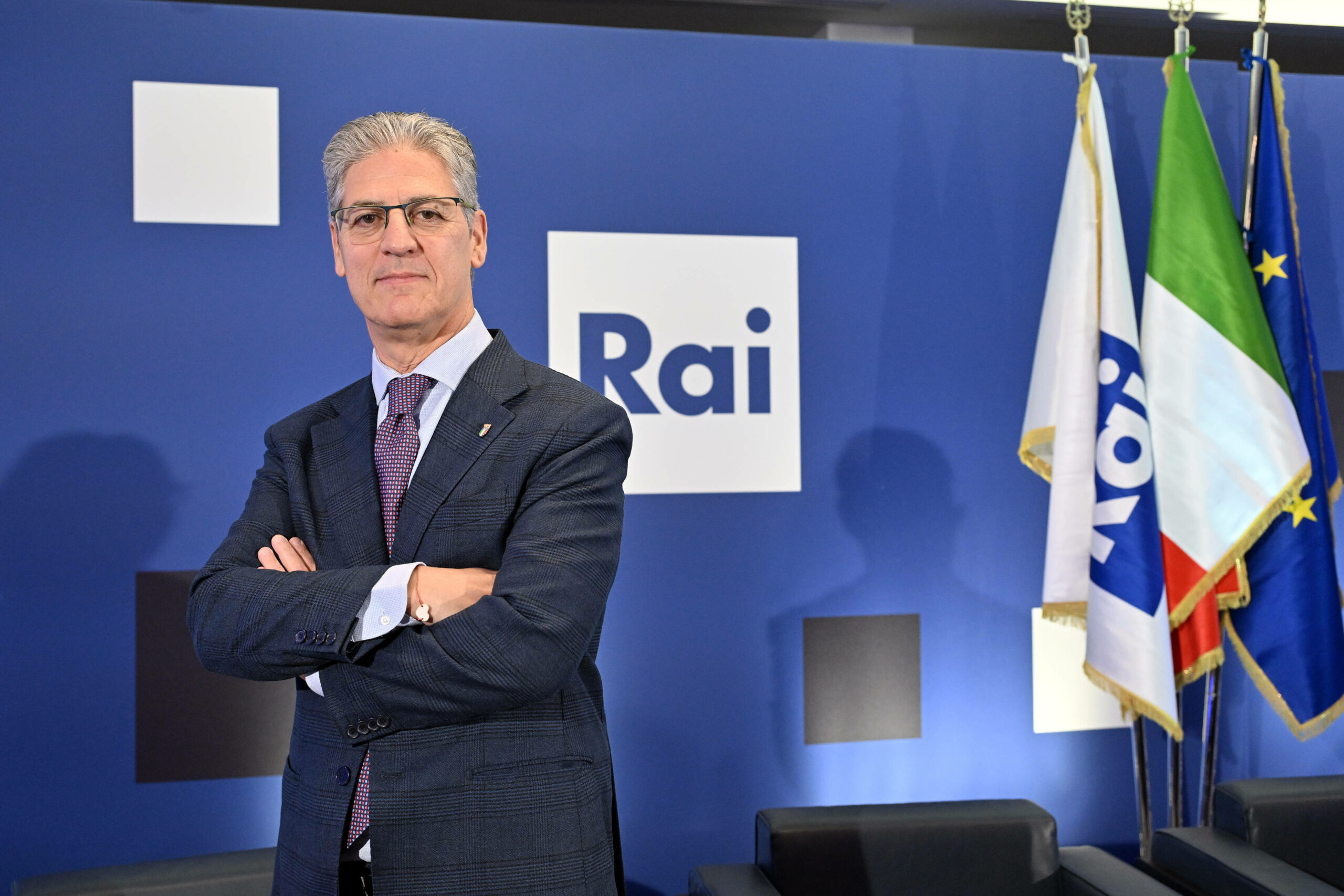 Paolo Petrecca posiert vor einer Wand mit dem Schriftzug des Senders "Rai".