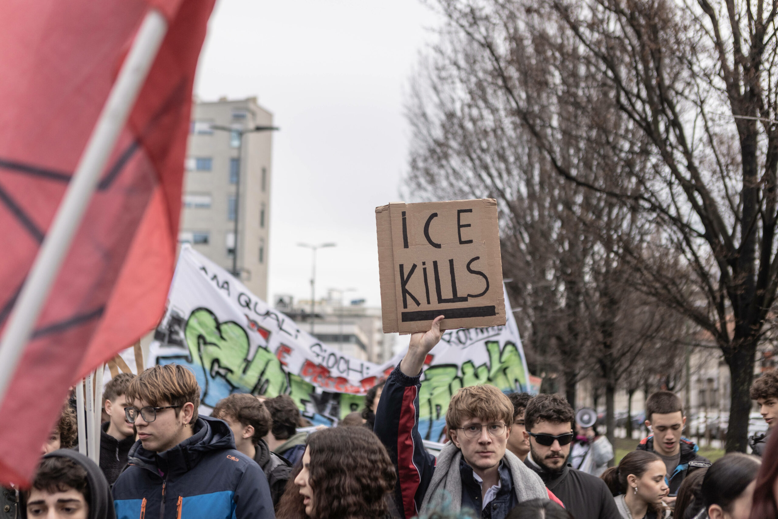 Ein Demosntrante hält ein Stück Karton mit der Aufschrift „ICE kills“ in auf einer Demonstration in die Höhe