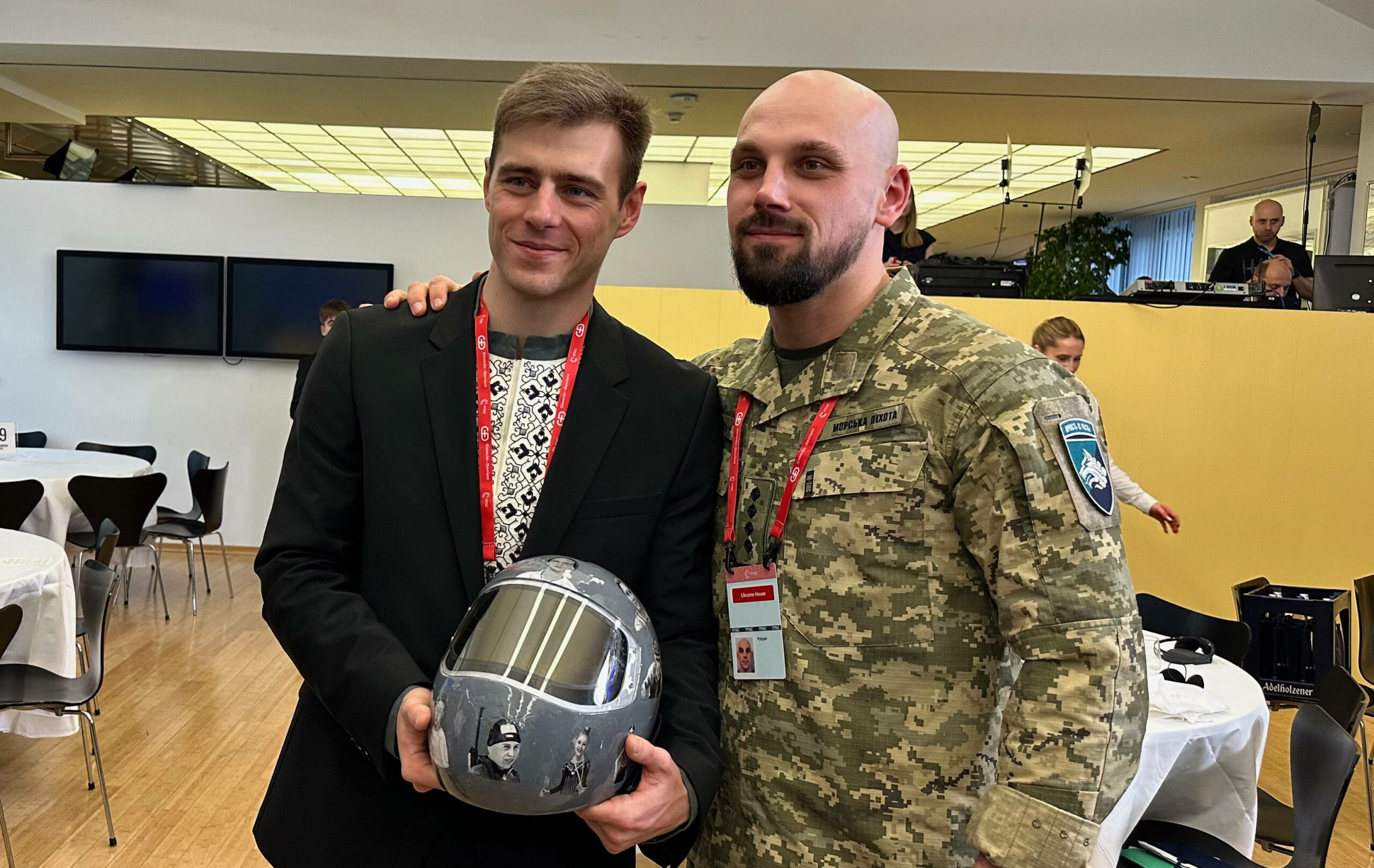 Vladyslav Heraskevych posiert mit seinem Olympia-Helm und einem Soldaten