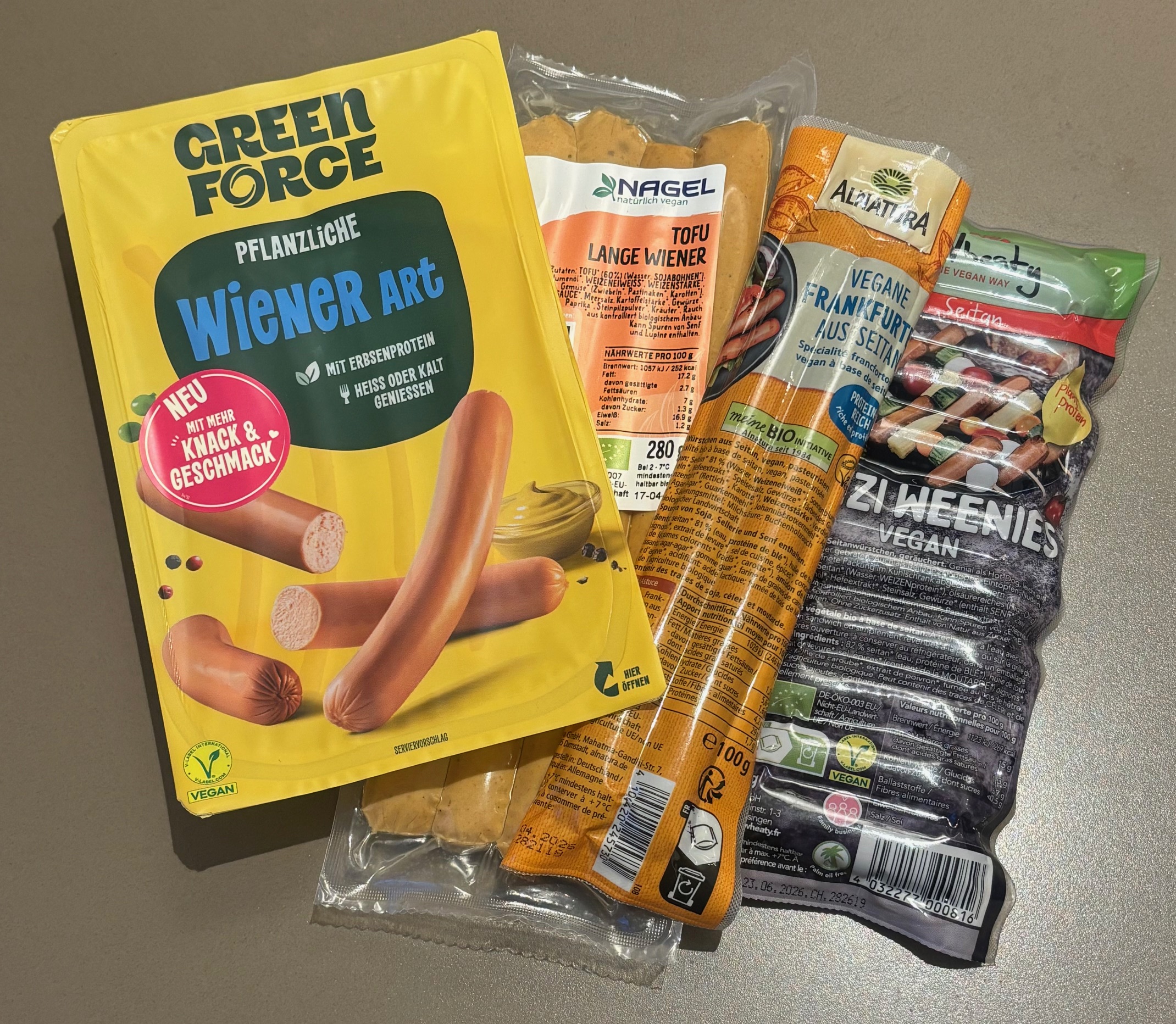 Vier Produkte pflanzlicher Würstchen.