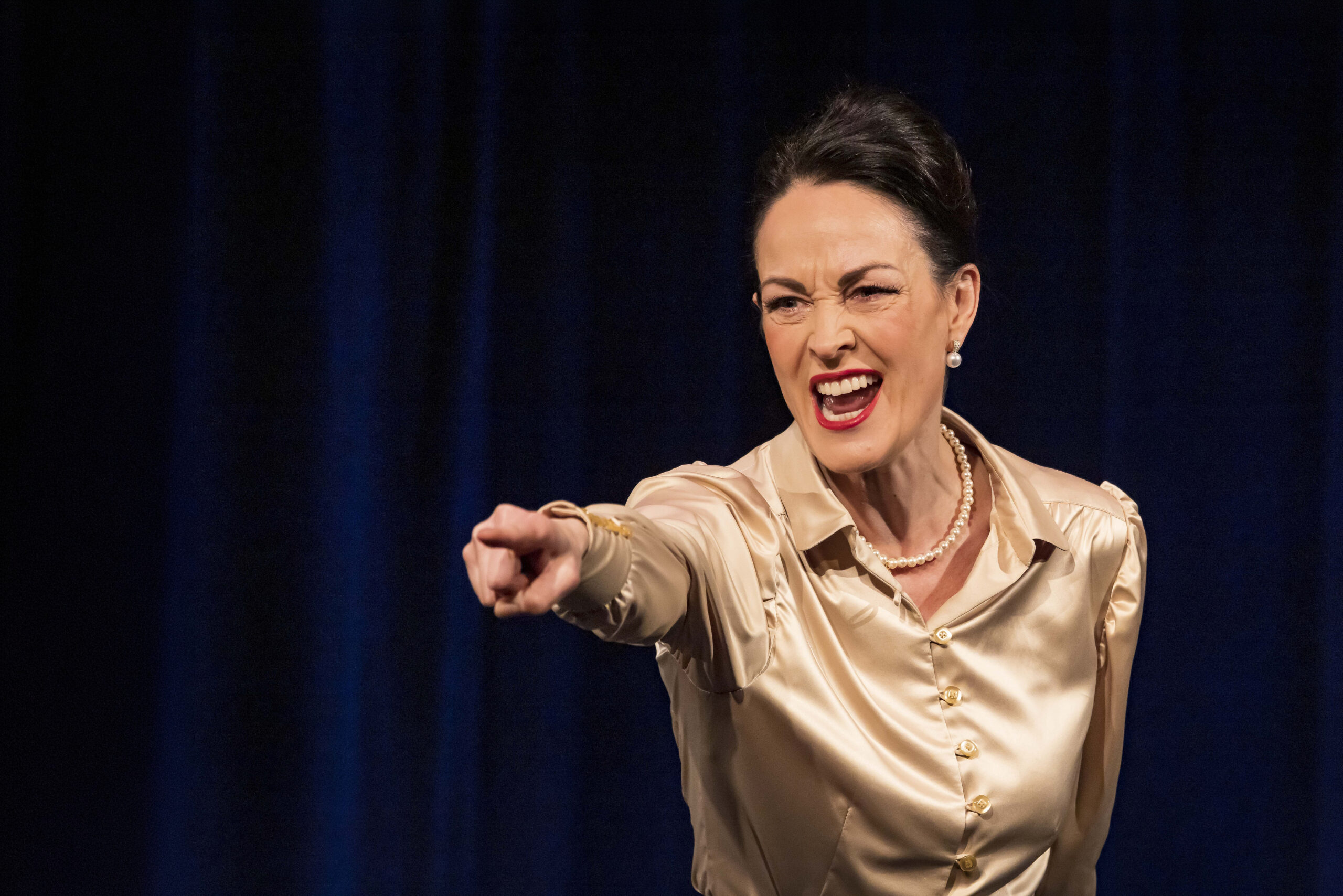 Solo auf der Bühne, viel Mimik, sie zeigt mit ausgestrecktem Arm nach vorne