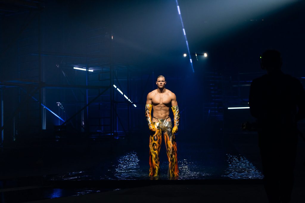 Kandidat Yanneck (24) oberkörperfrei und mit langer Hose auf dem Laufsteg.