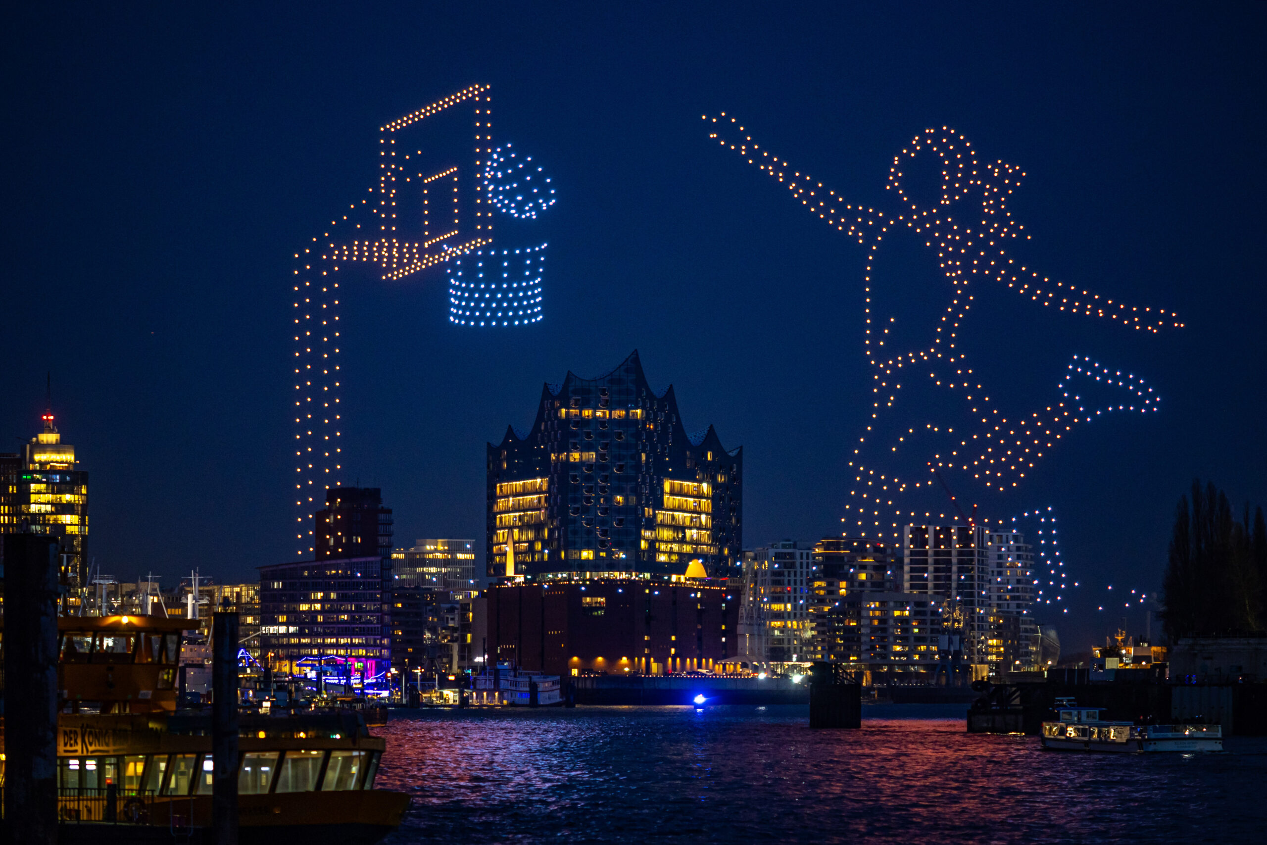 Spektakel über dem Hafen: Eine Drohnen-Show lässt eine Basketballerin am Nachthimmel zum Wurf ansetzen – und der Ball landet im Korb.