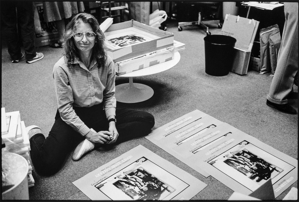 Eine Frau sitzt auf dem Boden. Vor ihr liegen Drucke.