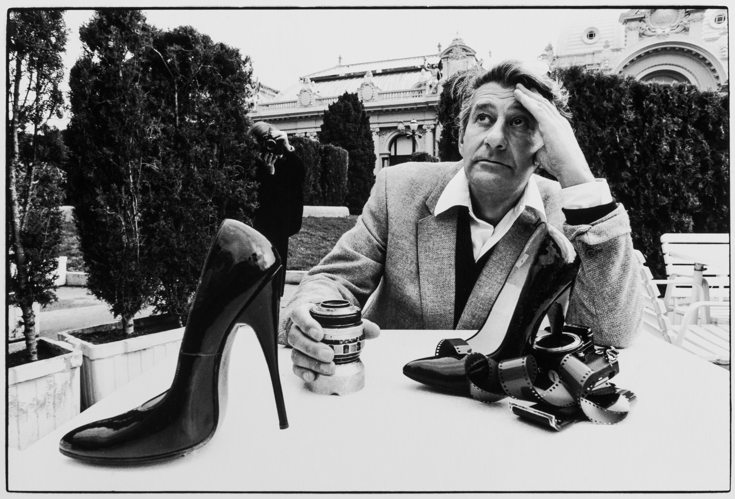 Fotografie eines Mannes, der an einem Tisch in einem Garten in Monte Carlo sitzt.