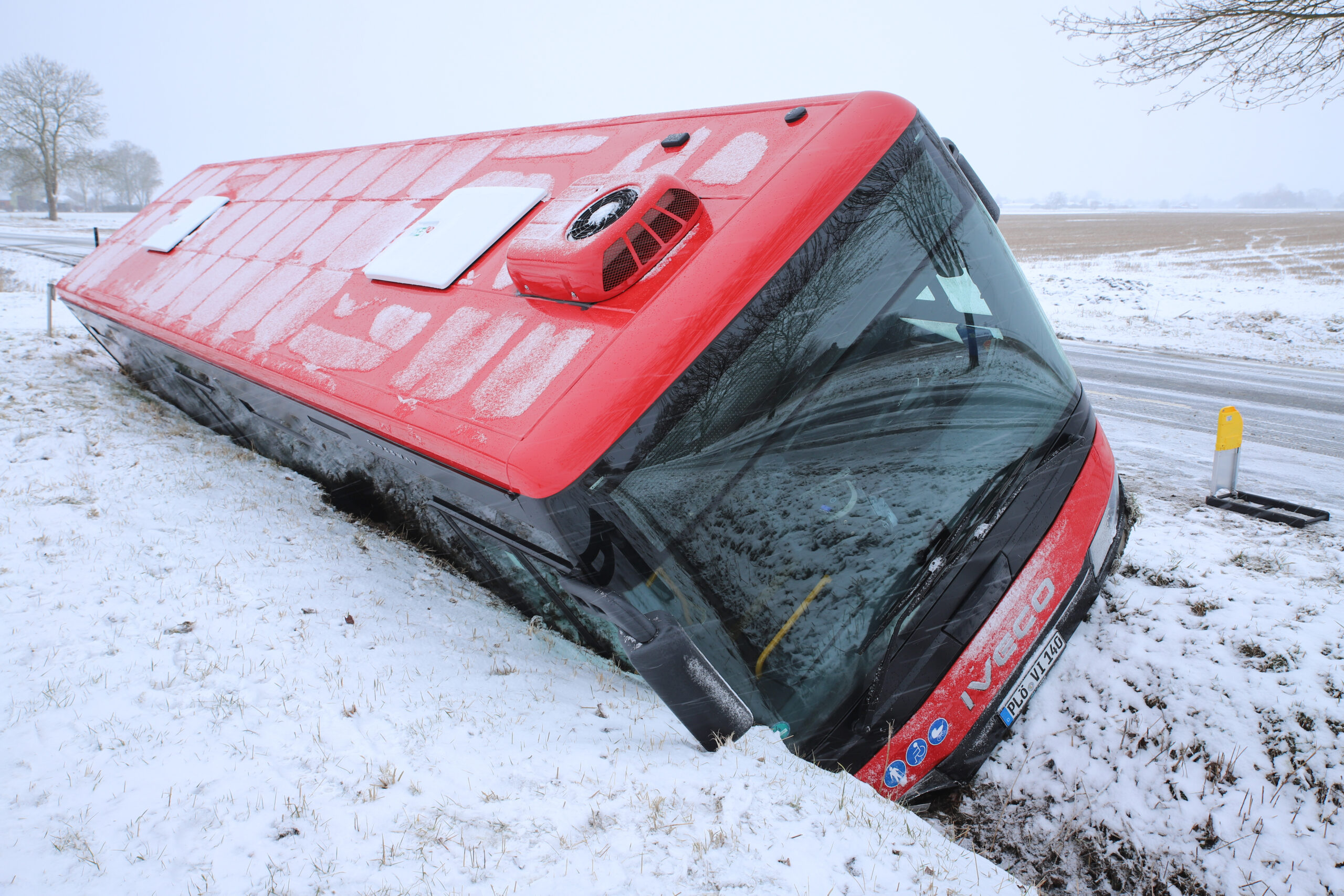 Roter Bus im verschneiten Straßengraben