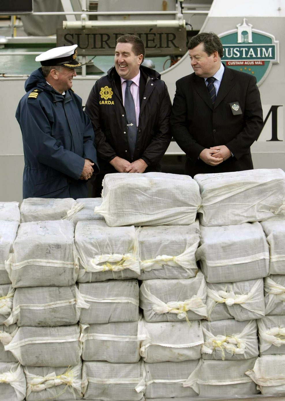Drei Männer in Uniform stehen vor einer gestapelten Ladung Kokain, die 2008 vor der irischen Küste sichergestellt werden konnte.