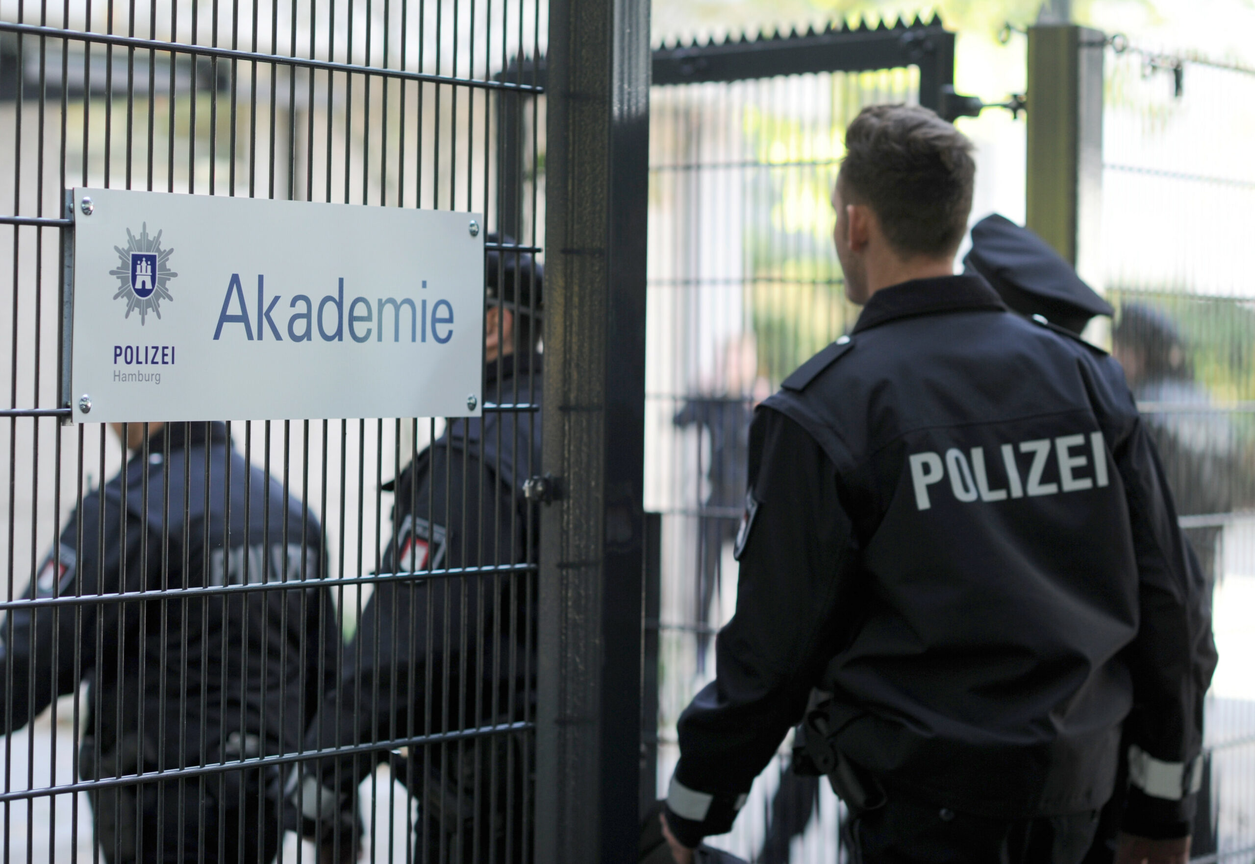 Polizisten gehen durch das Eingangstor der Polizeiakademie.