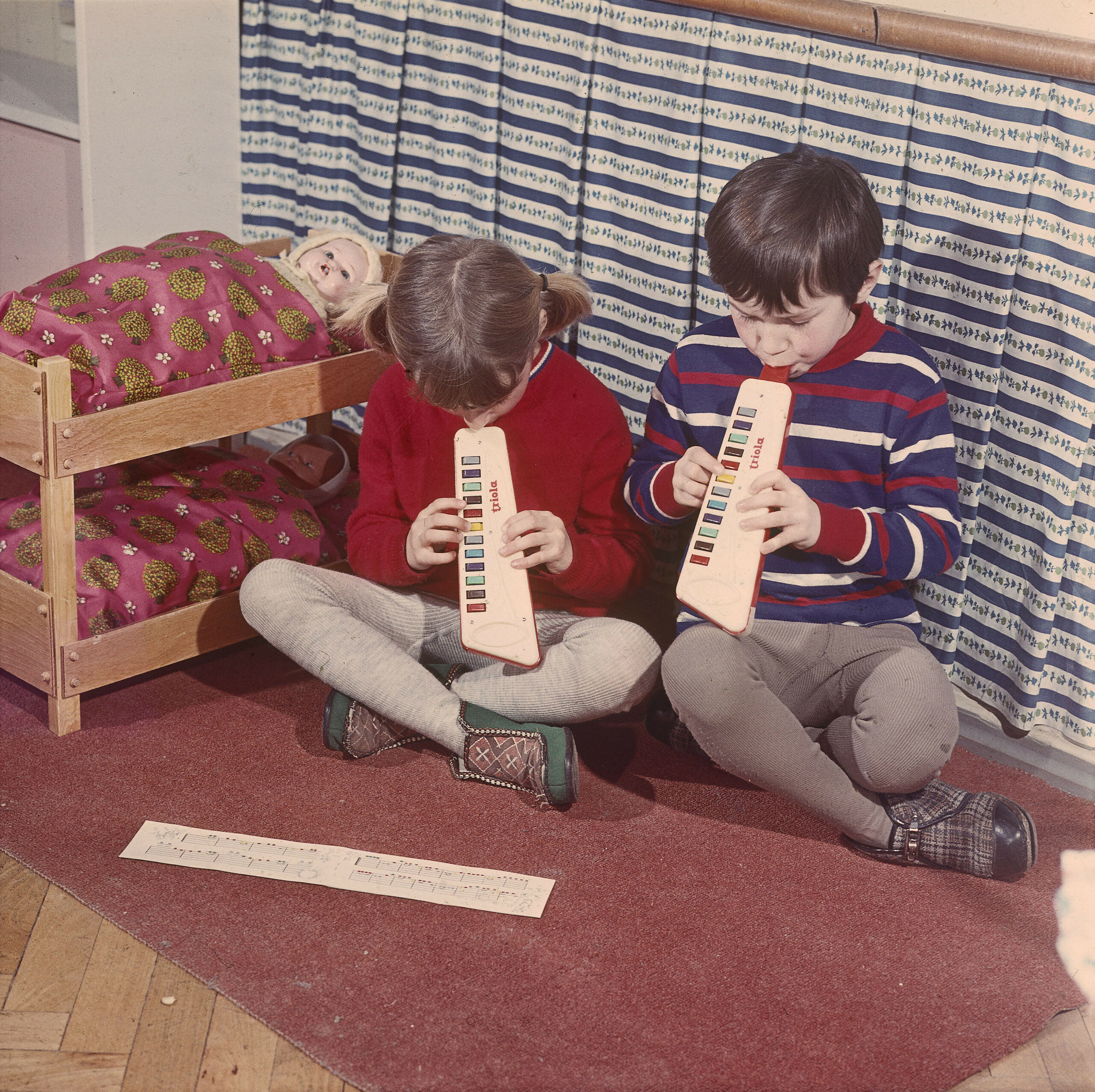 Zwei Kinder musizieren in den 1970er Jahren auf ihrem Spielzeug.