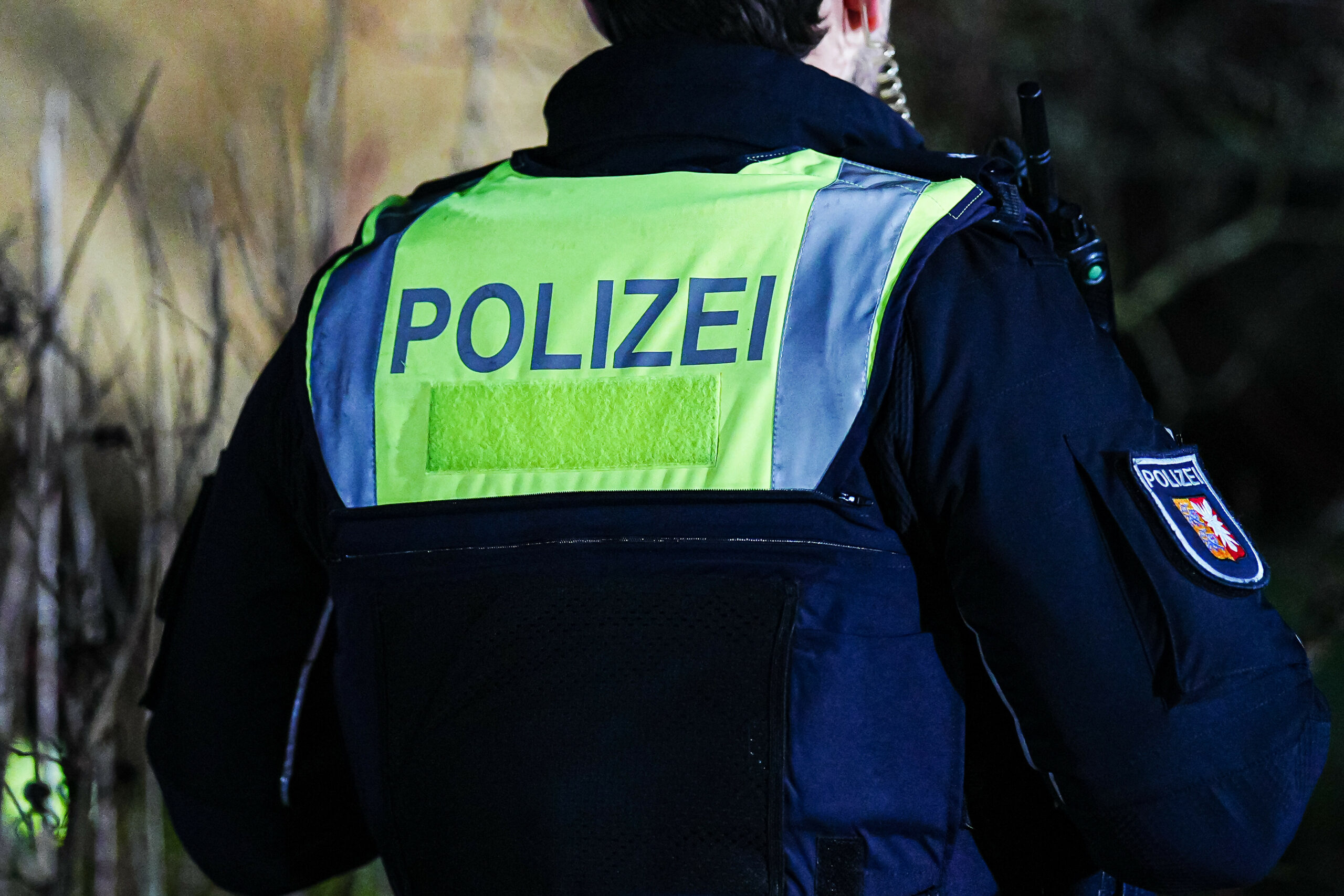 Aufschrift "Polizei" auf schusssicherer Weste von Polizisten mit Landeswappen von Schleswig-Holstein