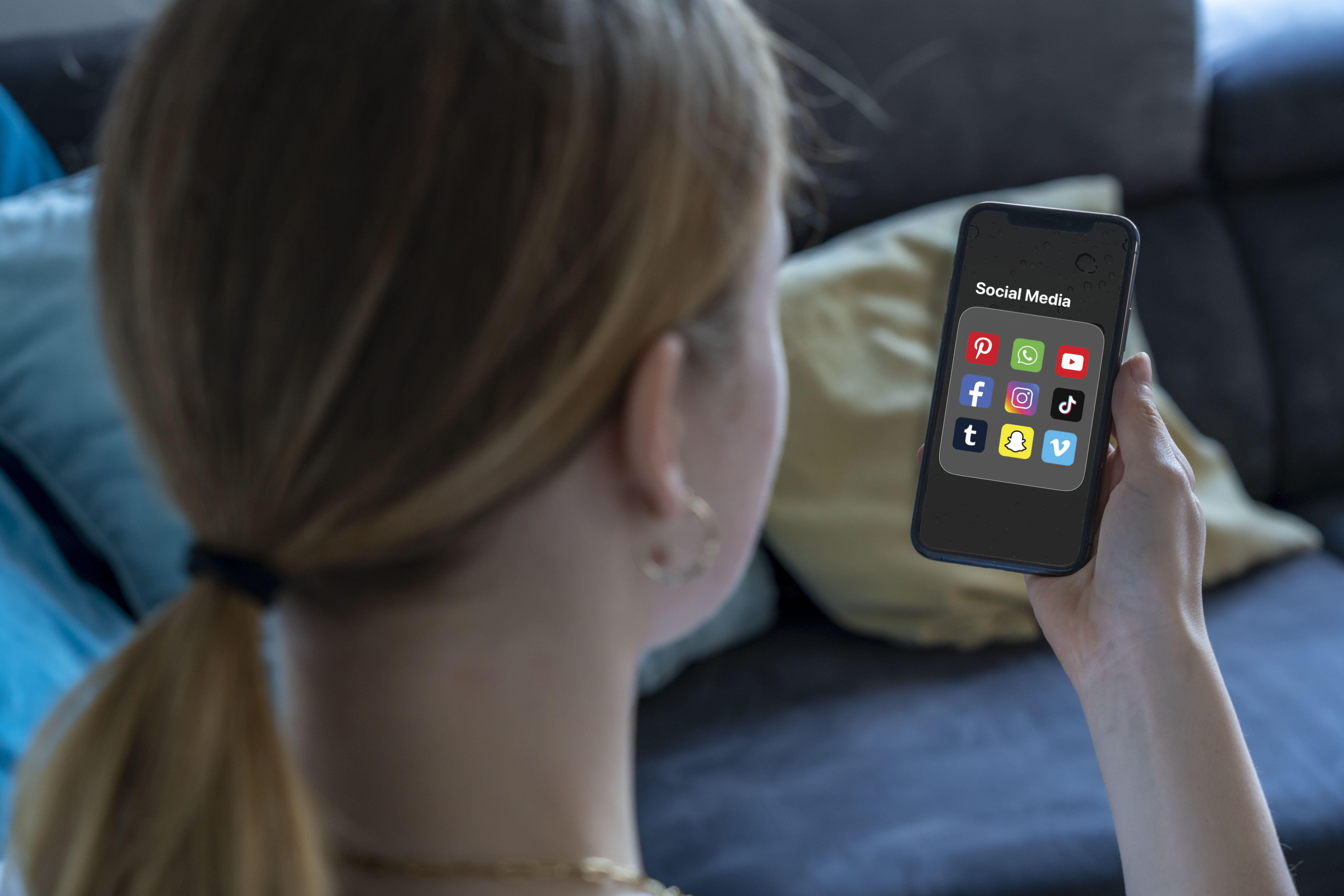 Ein Mädchen schaut auf ein Handy mit Social-Media-Apps (Symbolbild).