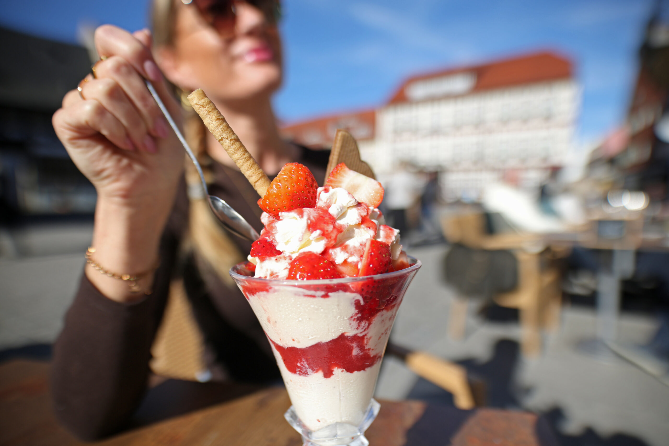Eine Frau enießt einen Eisbecher bei strahlendem Sonnenschein (Symbolbild).