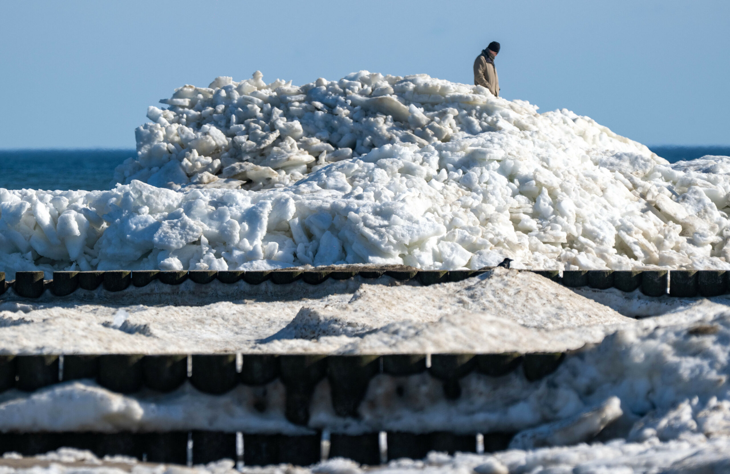 Touristen und Einwohner spazieren am Strand von Zempin. Dort türmen sich auch am meteorologischen Frühlingsanfang noch Eisschollen auf mehreren Metern Höhe.