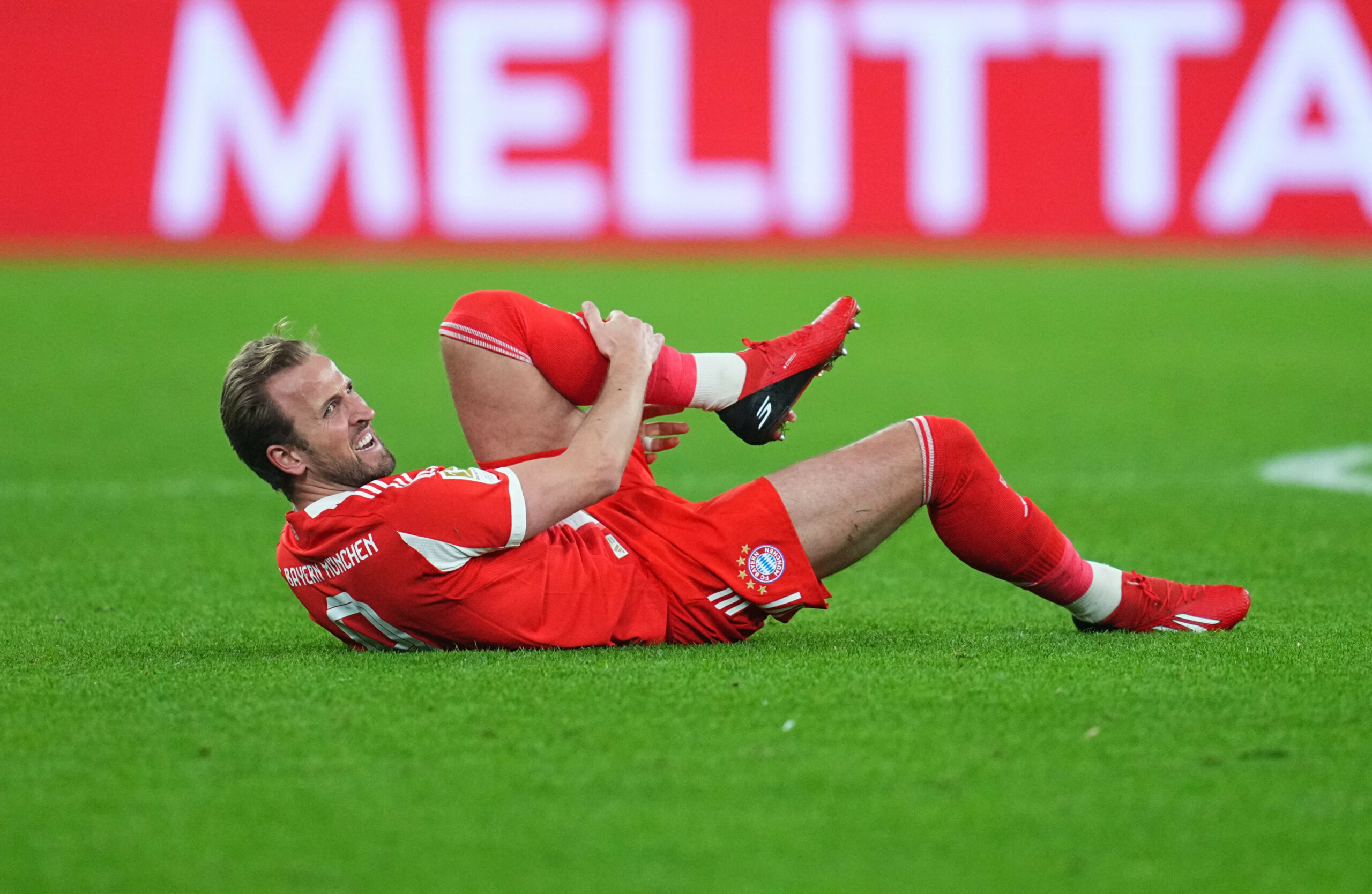Harry Kane liegt mit schmerzverzerrtem Gesicht am Boden und hält sich das Bein