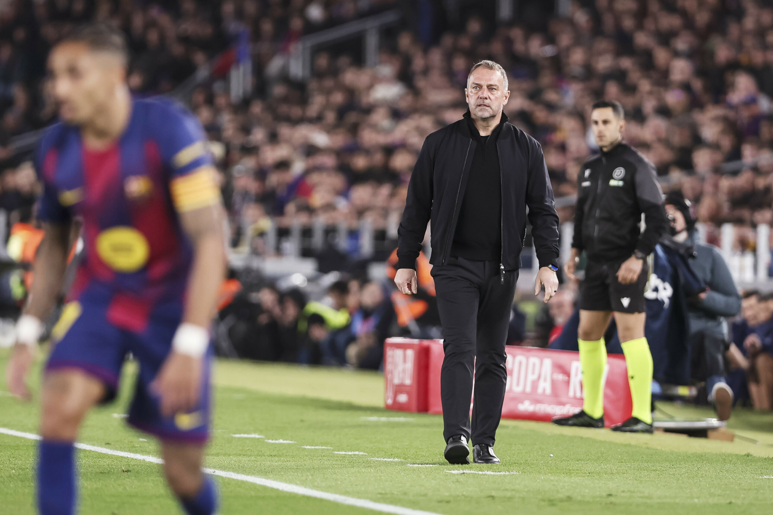 Hansi flick läuft an der Seitenlinie im Pokalspiel gegen Atlético Madrid entlang. Im Vordergrund Spieler Raphinha.