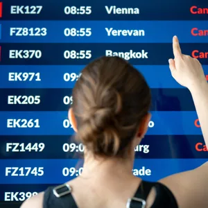 Frau von hinten vor Anzeigentafel am Flughafen