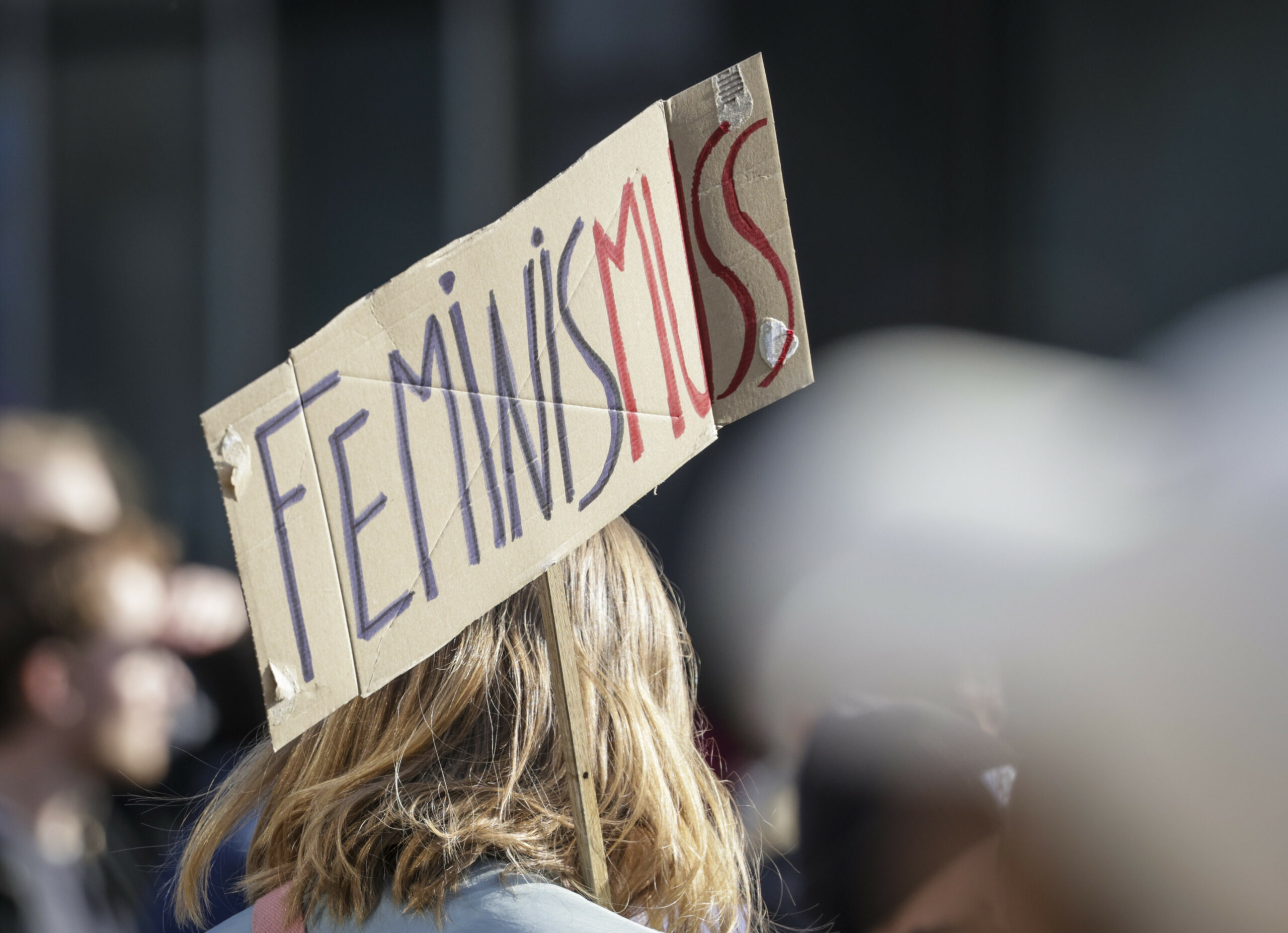 Ein Teilnehmerin einer Demonstration zum Weltfrauentag trägt ein Schild mit der Aufschrift «Feminis-muss».